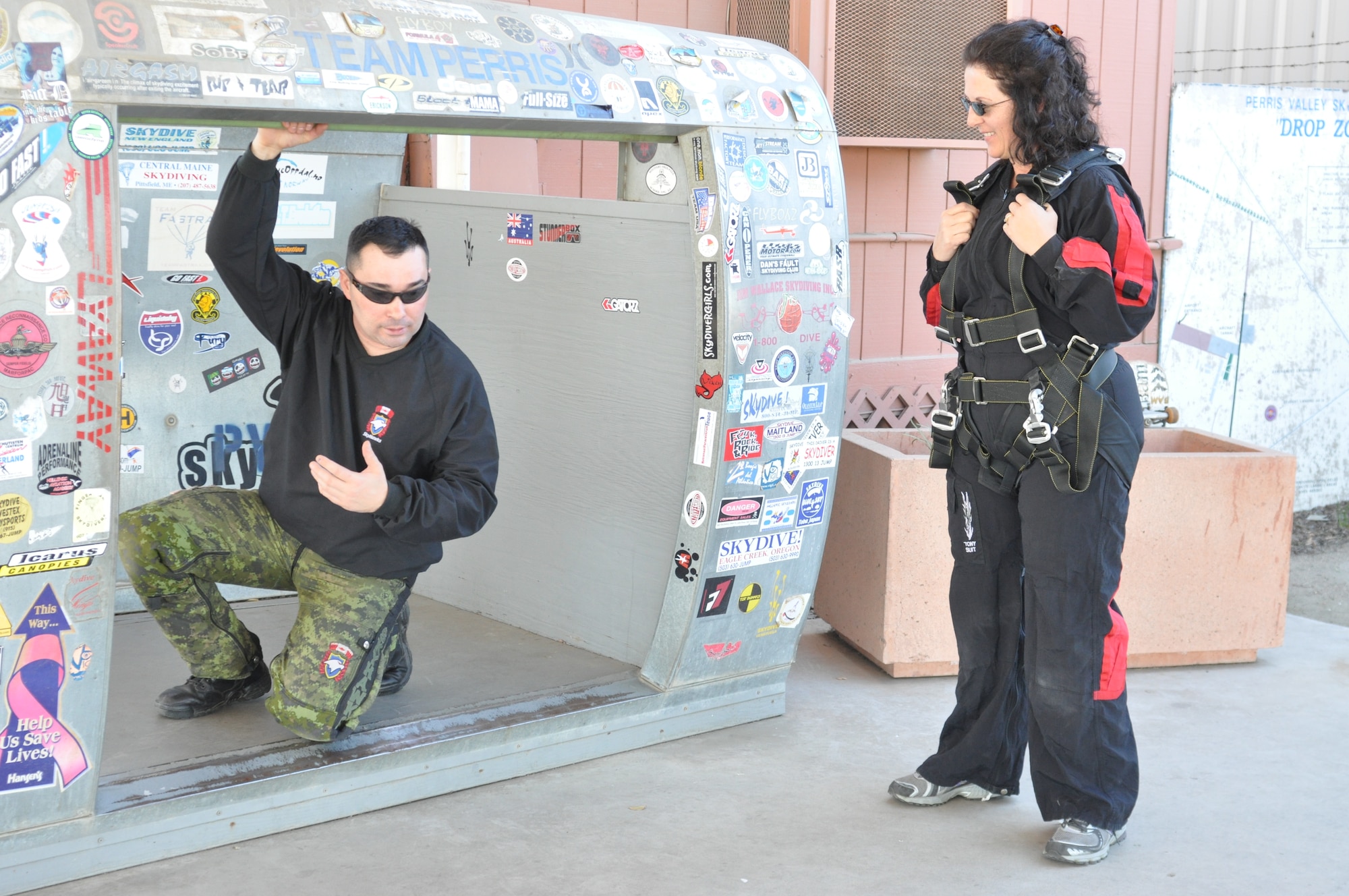 SkyHawks jumpmaster, "Scooter," similates skydiving movements as he prepares Linda Welz for her tandem jump.  (U.S. Air Force photo/ Megan Crusher)