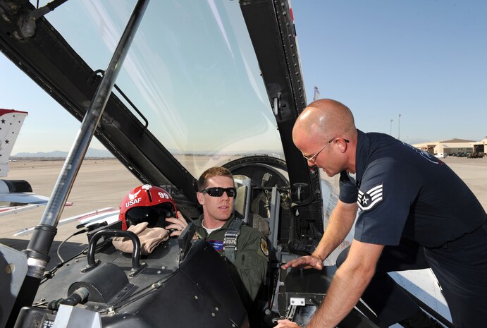 Staff Sgt. Lance Murphy, U.S. Air Force Air Demonstration Squadron "Thunderbirds" crew chief, inspects the cockpit connections for NASCAR driver Carl Edwards flight at Nellis Air Force Base, Nev., Mar. 3. Edwards, who drives the #99 car, will compete in NASCAR races March 5-6 at the Las Vegas Motor Speedway.(U.S. Air Force Photo/Staff Sgt. Larry E. Reid Jr., Released)