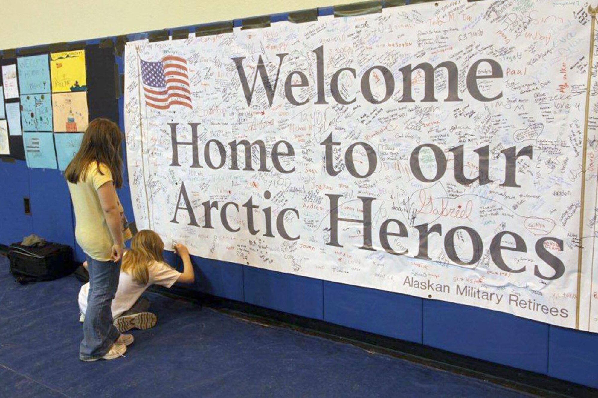 Family members sign a welcome home banner for returning Soldiers, Feb. 25 at Buckner Physical Fitness Center. (U.S. Army photo/Sgt. Tamika Dillard)