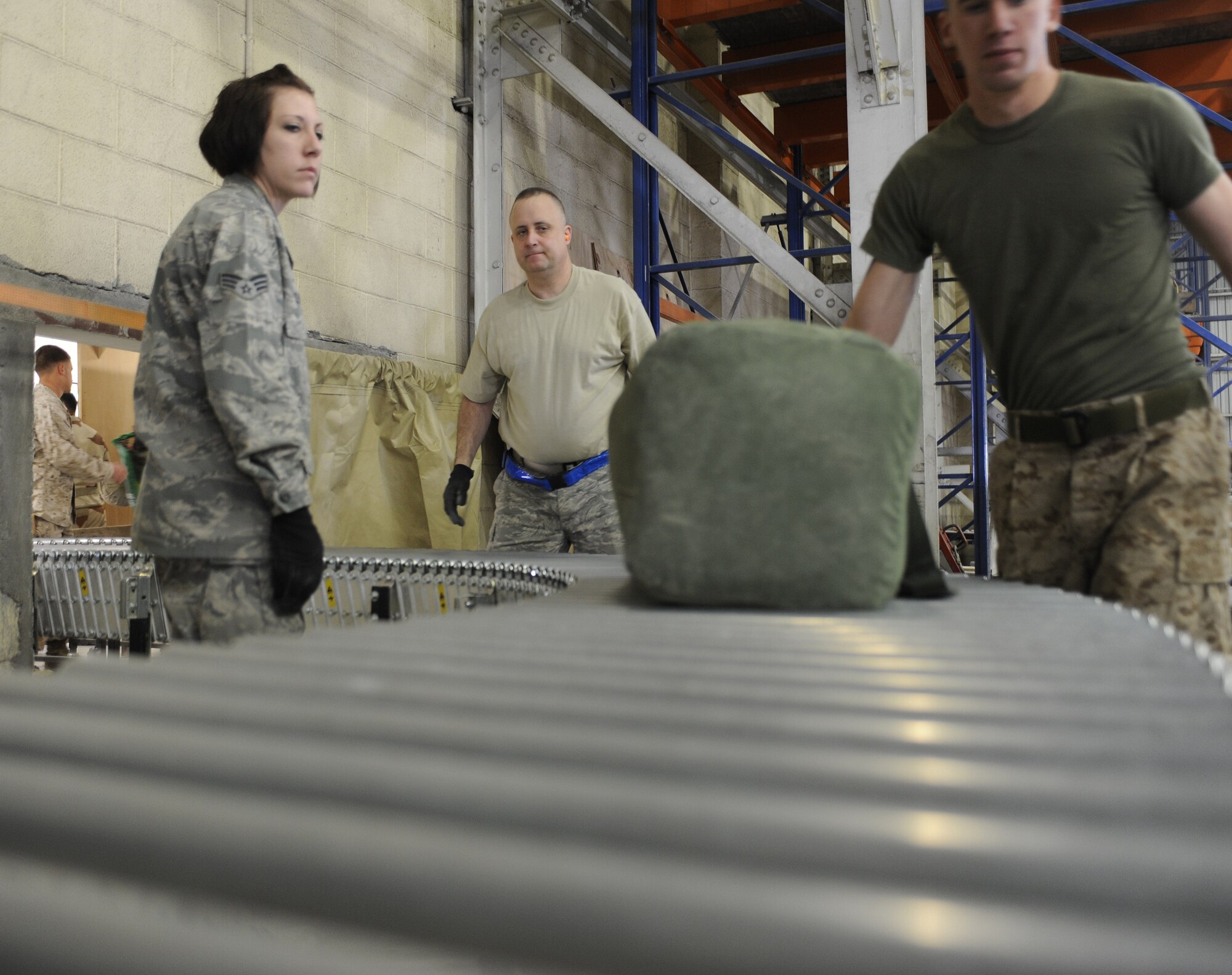 Staff Sgt. Brian Berson and Senior Airman Sarah Uhlenhake move baggage down a conveyer to be palletized, March 4, 2011, at Kandahar Airfield, Afghanistan. Once the bags are loaded onto a pallet, they?ll be driven to the aircraft and loaded. The Airmen are assigned to the 451st Expeditionary Logistics Readiness Squadron Aerial Port. (U.S. Air Force photo/Senior Airman Willard E. Grande II/Released)