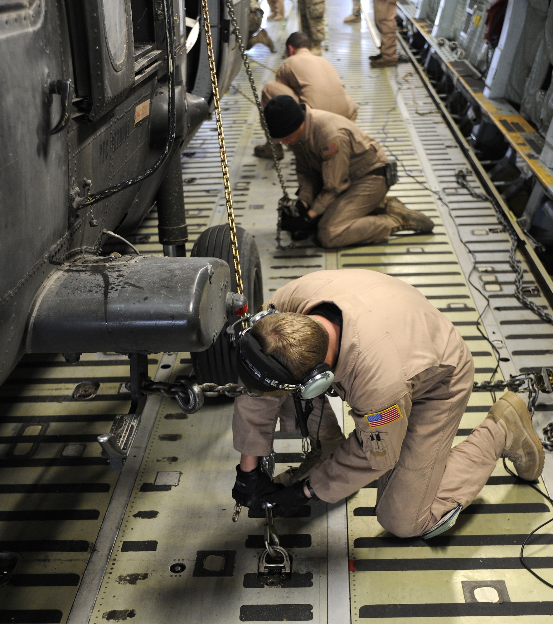 Staff Sgt. Justin Leonard, Airmen 1st Class Colby Wentland and Justin Marriott tie down a UH-60L Blackhawk, Mar. 2, 2011, at Kandahar Airfield, Afghanistan. The Blackhawk upload was part of a change out; the old helicopters are being replaced by new airframes. The Airmen are loadmasters assigned to the 9th Airlift Squadron, 436th Airlift Wing out of Dover Air Force Base, Del. (U.S. Air Force photo/Senior Airman Willard E. Grande II/Released)