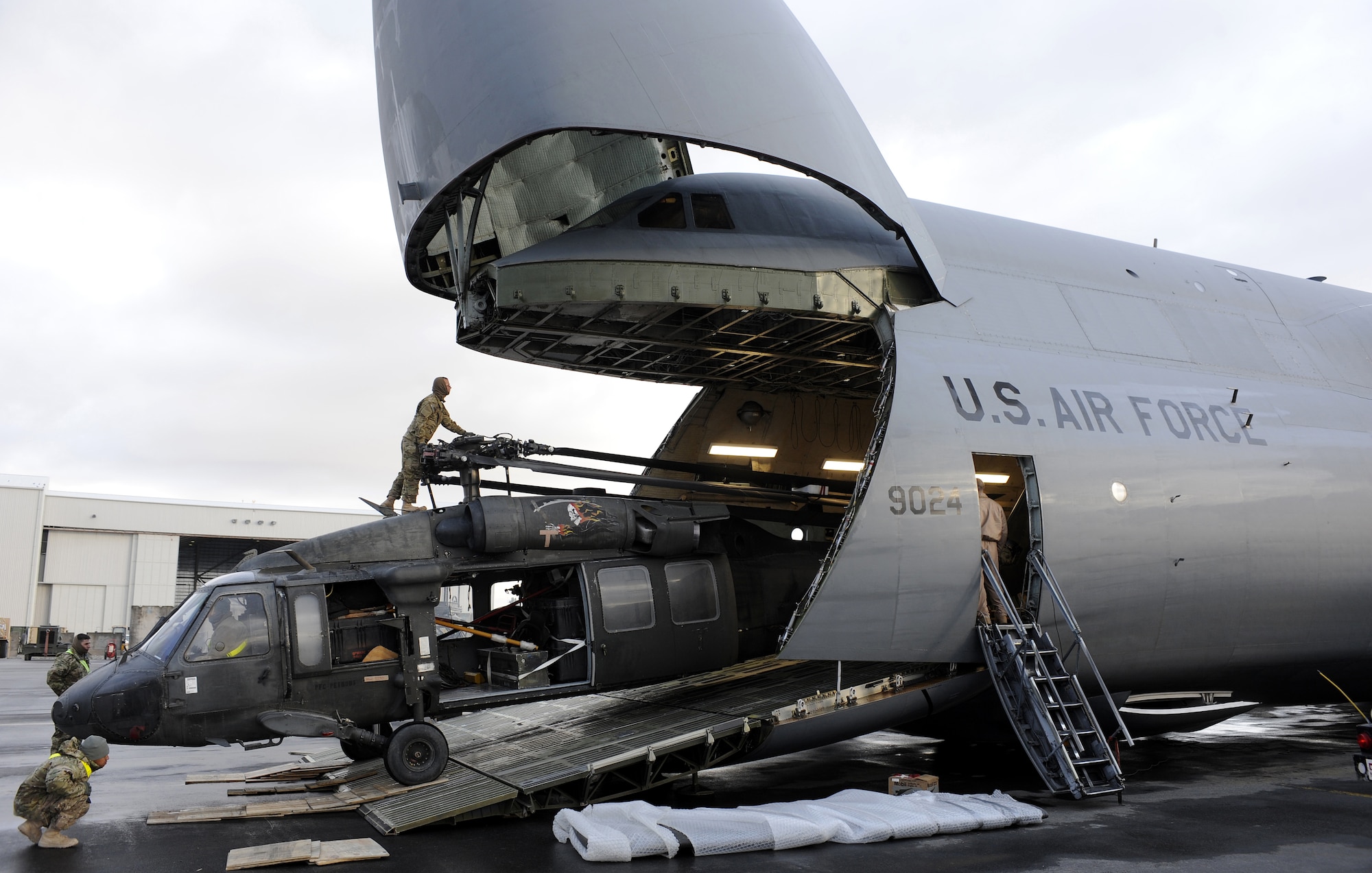 Soldiers spot a UH-60L Blackhawk while it is being loaded onto a C-5 Galaxy, Mar. 2, 2011, at Kandahar Airfield, Afghanistan. The Blackhawk upload was part of a change out; the old helicopters are being replaced by new airframes. The Soldiers are assigned to the 563rd Aviation Support Battalion out of Fort Campbell, Ky. (U.S. Air Force photo/Senior Airman Willard E. Grande II/Released)