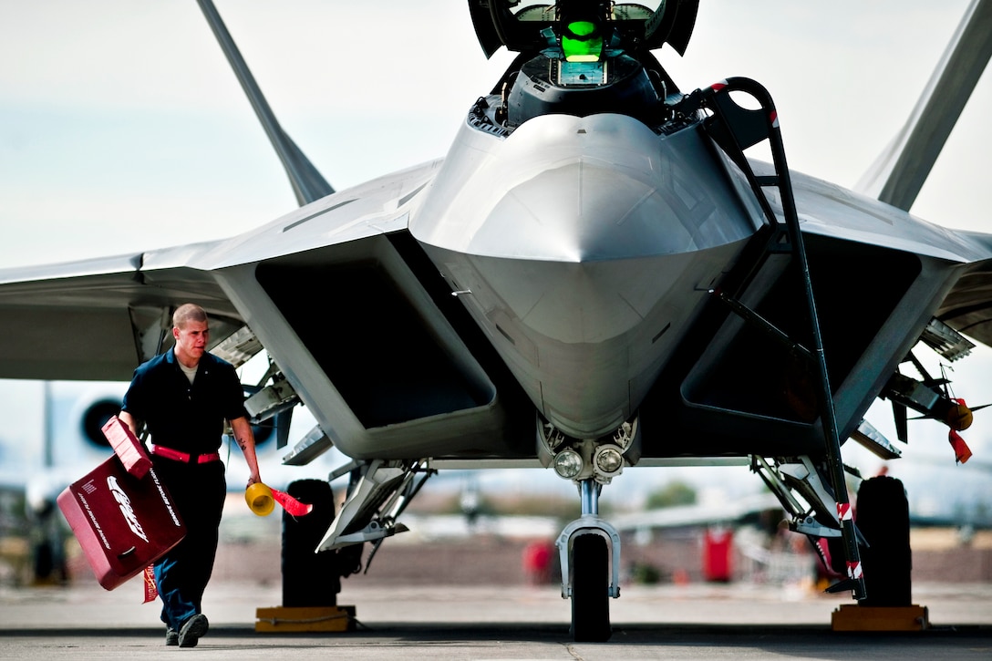 U.S. Air Force Airman 1st Class Jonathan Foster removes the intake covers of a U.S. Air Force F-22 Raptor before a training mission on Nellis Air Force Base, Nev., March 2, 2011. Foster is a crew chief is assigned to the 49th Aircraft Maintenance Squadron.