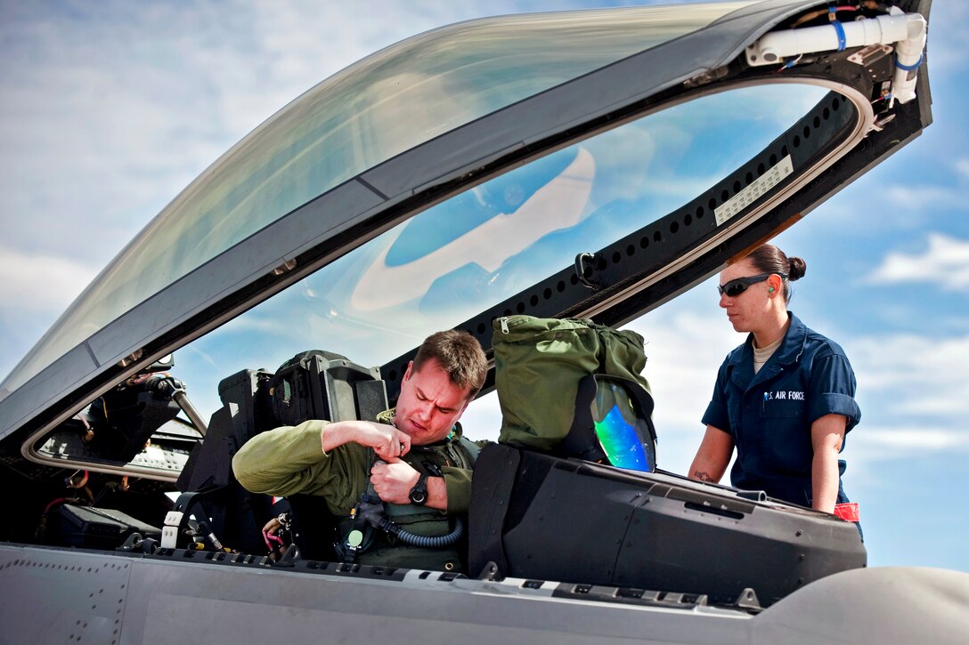 U.S. Air Force Senior Airman Samantha Whisman, right, assists Air Force Capt. Drew Maulsby as he prepares for a training mission on Nellis Air Force Base, Nev., March 2, 2011. Whisman is a crew chief and Maulsby is an Air Force F-22 Raptor pilot. Both are assigned to the 90th Aircraft Maintenance Squadron.
