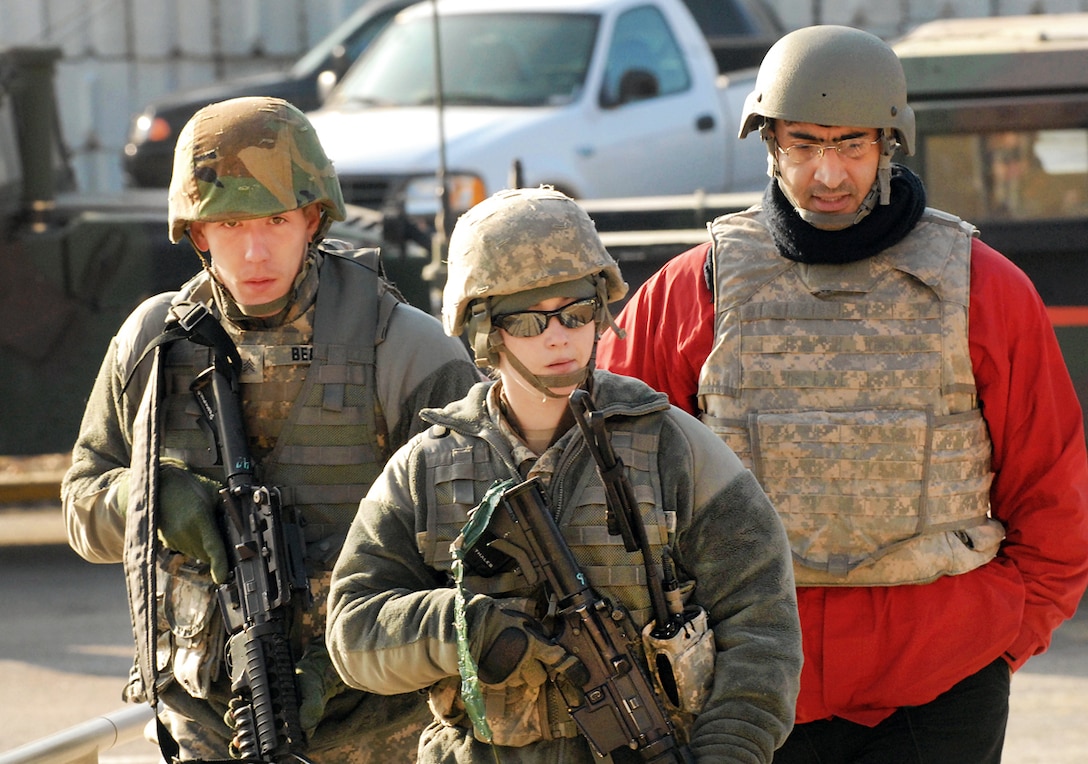 An Indiana National Guard soldier escorts a role playing Afghan translator to a meeting with civilian students at the Muscatatuck Urban Training Center, on Camp Atterbury, in Ind., Feb. 10, 2011.
