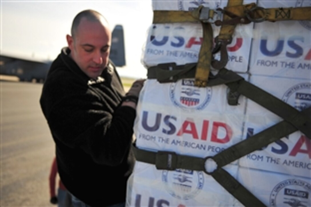 A U.S. airman loads blankets, tarp and water containers provided by USAID onto a U.S. Air Force C-130 aircraft in Pisa, Italy, March 4, 2011. The U.S. airman is from the 435th Air Mobility Squadron. The U.S. government is working with the international community to meet the humanitarian needs of the Libyan people and others in their country who fled across the border because of political unrest.