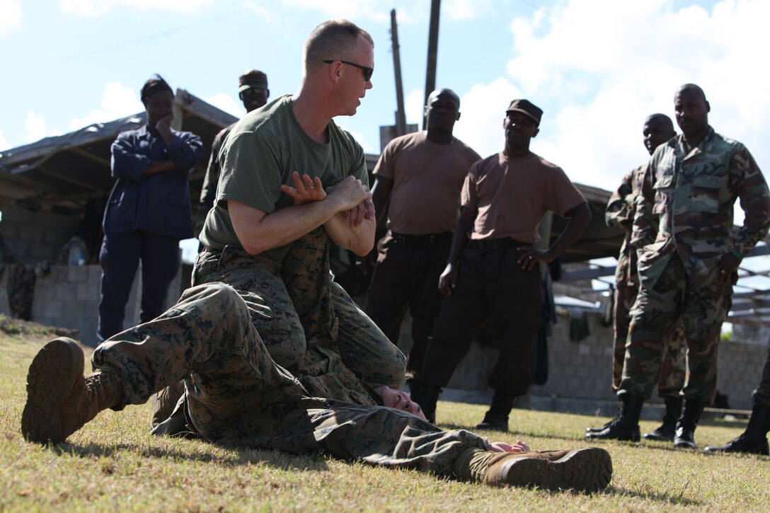 Gunnery Sgt. Brian Dye, the chief non-lethal weapons instructor for exercise Tradewinds 2011, takes Lance Cpl. Bruce Dunn, a squad automatic weapon gunner with Company I, 3rd Battalion, 24th Marine Regiment and Smyrna, Tenn. native, to the deck and demonstrates an arm hold technique during non-lethal weapons training as part of exercise Tradewinds 2011.::r::::n::