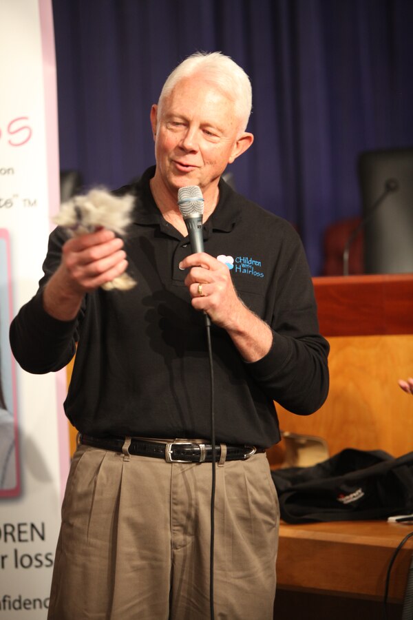 Lt. Gen. Jack W. Bergman holds his freshly cut hair in a braid to be donated to an organization that will turn it onto a wig for a child with hair loss, March 4, in the council chambers of City Hall.