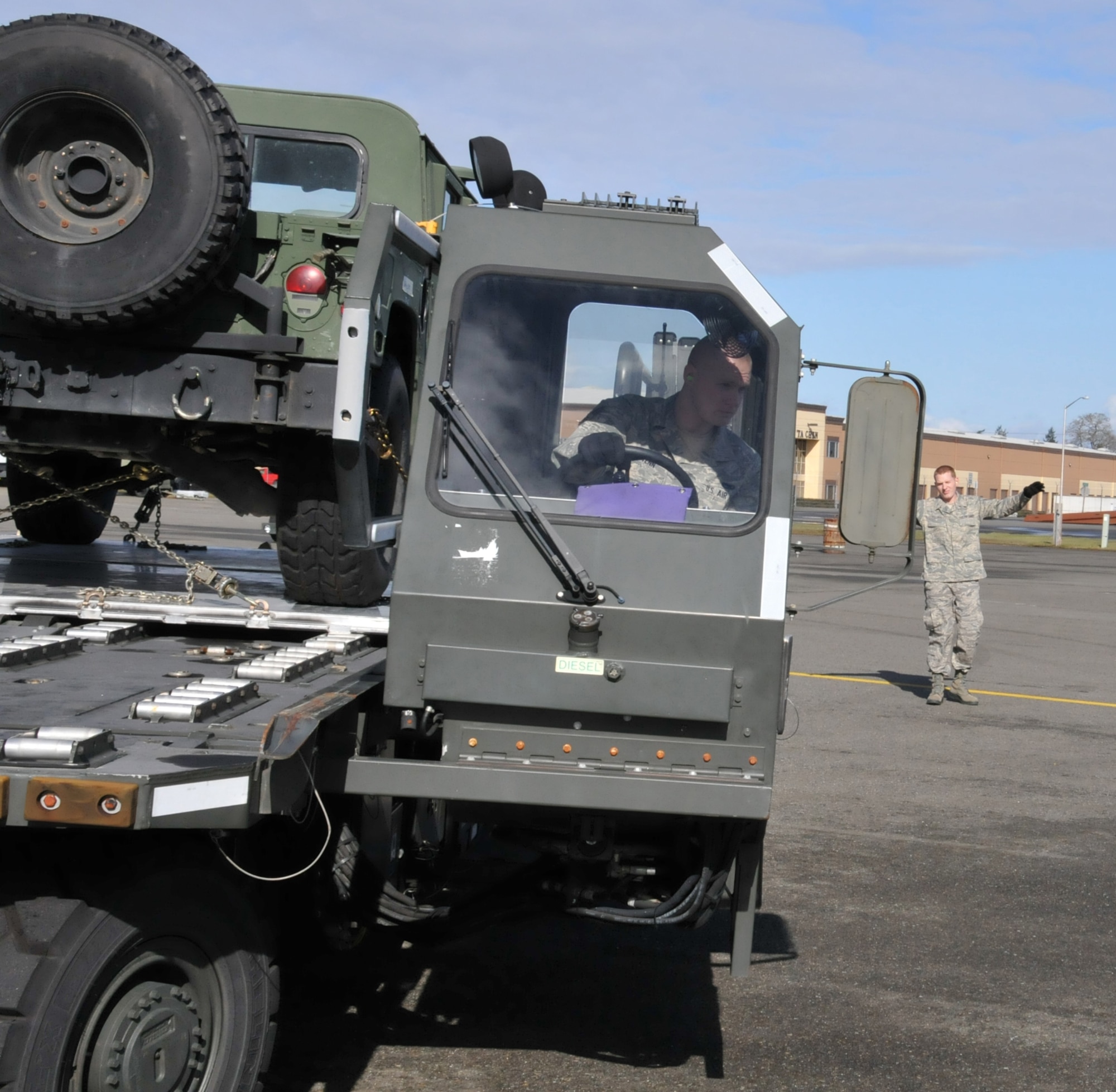 U.S. Air Force Senior Airman Travis Schwenn (foreground), 86th Aerial Port Squadron, McChord Field, Wash., reverses a Next Generation Small Loader (NGSL) as he takes his cues from 'spotter,' U.S. Air Force Senior Airman Cory Cochran during the squadron's monthly training exercise, March 5. The latest simulated training involved securing a damaged Humvee on board a C-17 Globemaster III aircraft. (U.S. Air Force photo by Staff Sgt. Nicole Celestine/Released)