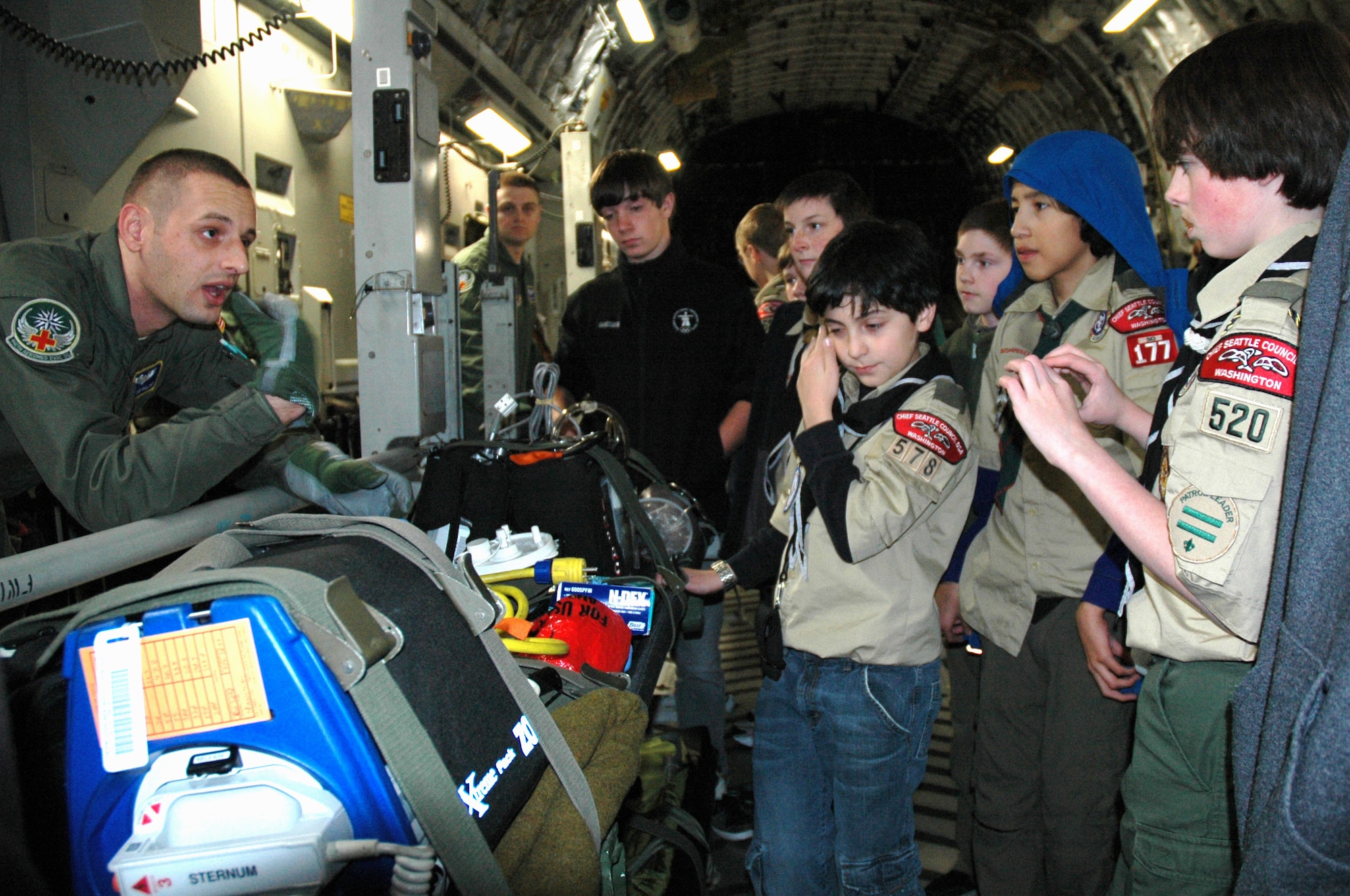 (Pictured left) U.S. Air Force Technical Sgt. Cam Vaillant, 446th Aeromedical Evacuation Squadron medical technician, here, tells Boy Scout troops about the AES mission evacuating sick and injured patients from harm's way and transferring them to an environment that supports their recovery during wartime, peacetime and humanitarian operations.  Three Boy Scout troops from Seattle and Redmond, Wash., toured McChord Field for some hands-on experience aboard a C-17 Globemaster III static display. (U.S. Air Force photo by Staff Sgt. Elizabeth Moody/Released)