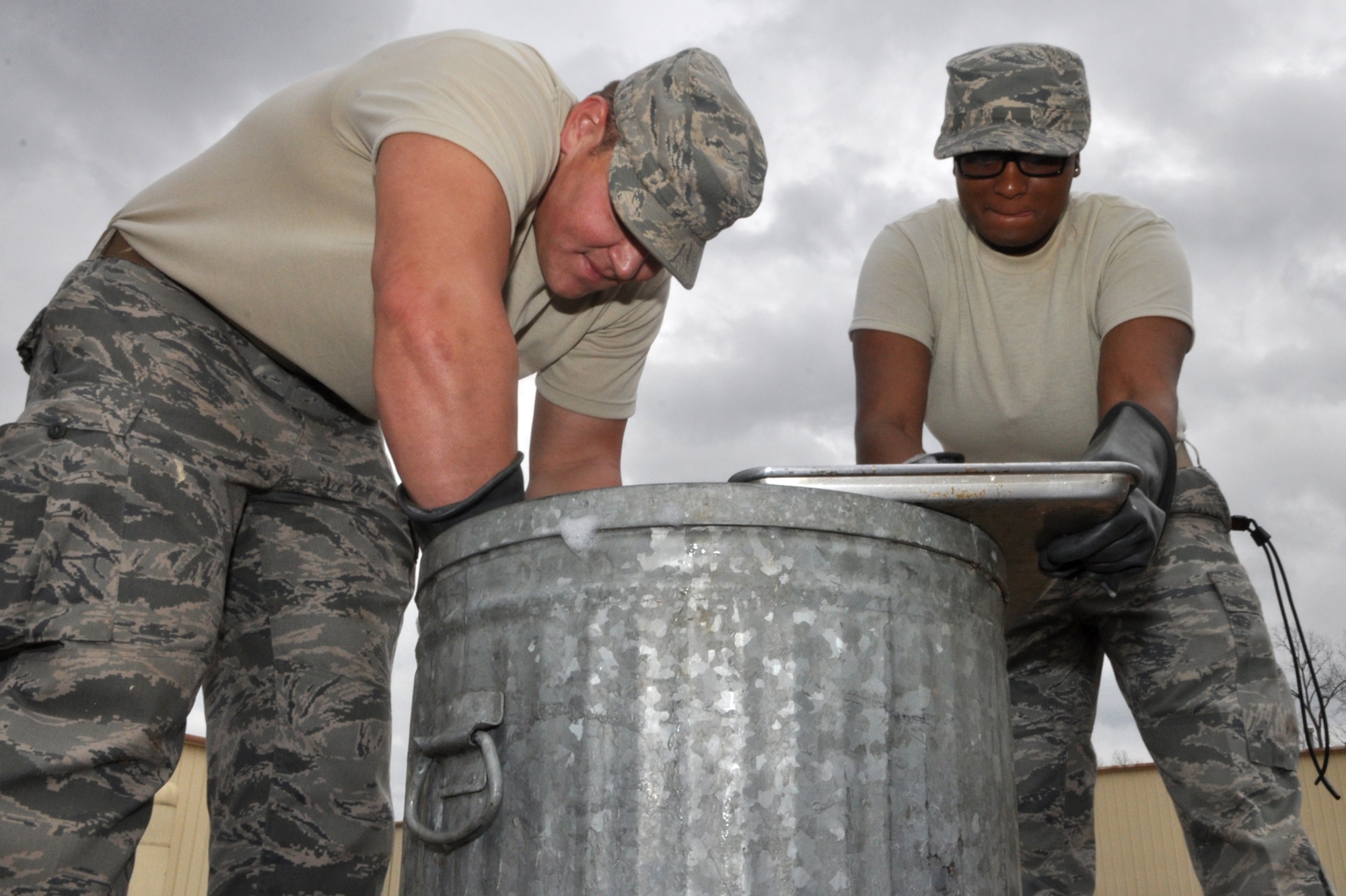 Senior Airmen Josh Davis and Robyn Bell perform enviable kitchen duties on the second day of a four-day exercise at the RED HORSE Squadron compound on Barksdale Air Force Base, La., March 4, 2011. Airman Davis is a structural apprentice, and Airman Bell is a personnel apprentice. Both Airmen are assigned to the 307th RED HORSE Squadron at Barksdale. Members of the 307th RED HORSE Squadron are participating in an exercise that is simulating a deployment to a Southwest Asia location where the Airmen are building helicopter landing pads for a U.S. Marine Unit. (U.S. Air Force photo/Tech. Sgt. Jeff Walston)