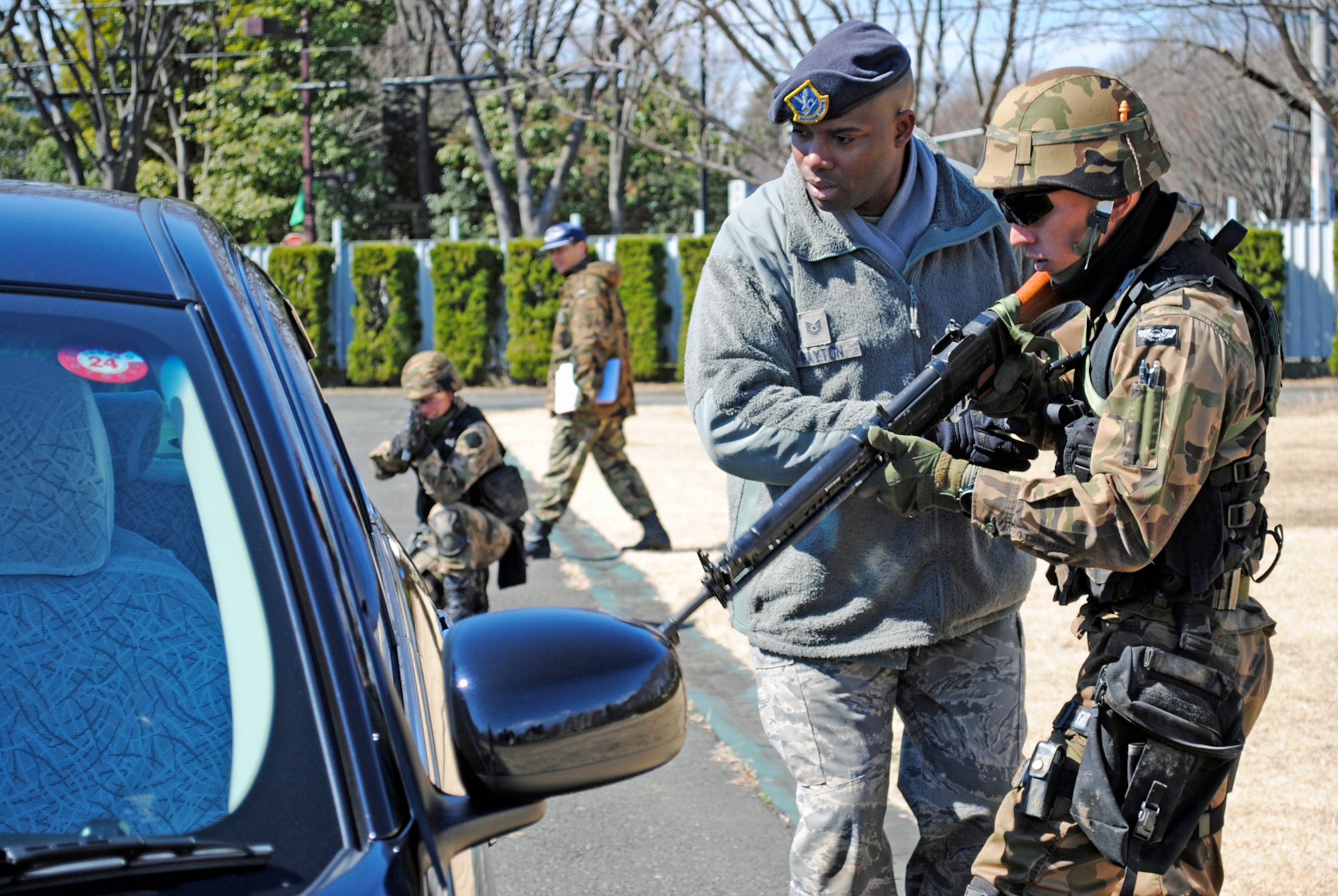 FUCHU AIR BASE, Japan -- Tech. Sgt. Johnnie Payton, 374th Security Forces Squadron flight chief, trains a security guard from the Japan Air Self Defense Force on how to properly approach a suspicious vehicle during field training here Mar. 4.  5th Air Force and 374th Airlift Wing Airmen are helping to train approximately 35 JASDF security guards as they prepare to stand up the Air Self Defense Force's first squadron devoted to advanced security training. (U.S. Air Force photo/Capt. Will Powell)