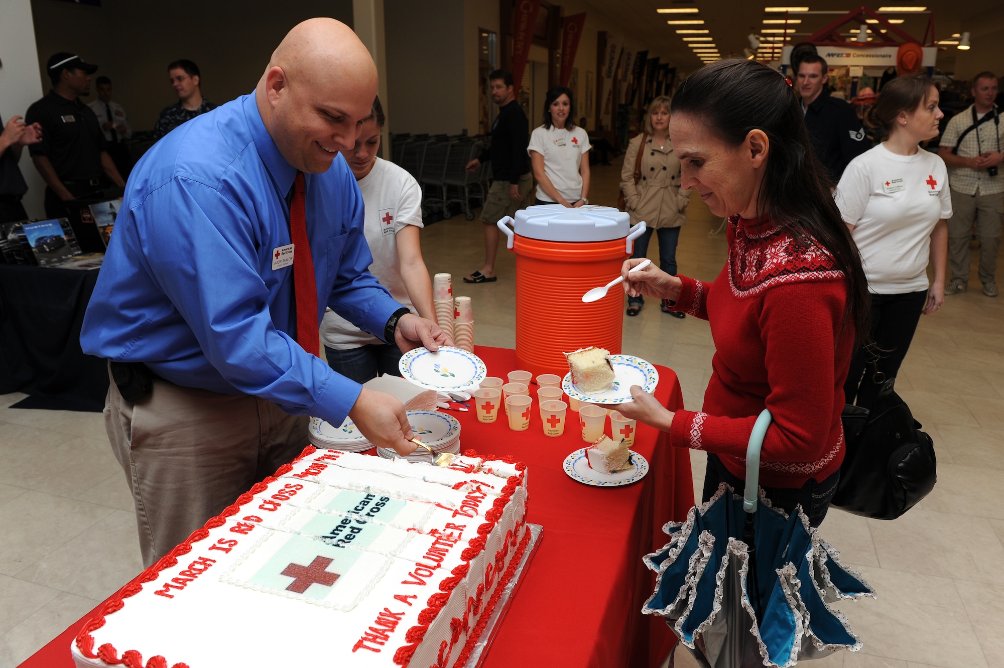 Mr. Jason Ramlow, station manager from the American Red Cross, hands a piece of cake to Mrs. Rachel Bradley during the Red Cross Month celebration at Kadena's Base Exchange, March 7. The celebration was held to bring awareness to Red Cross Month. (U.S. Air Force photo/Junko Kinjo)