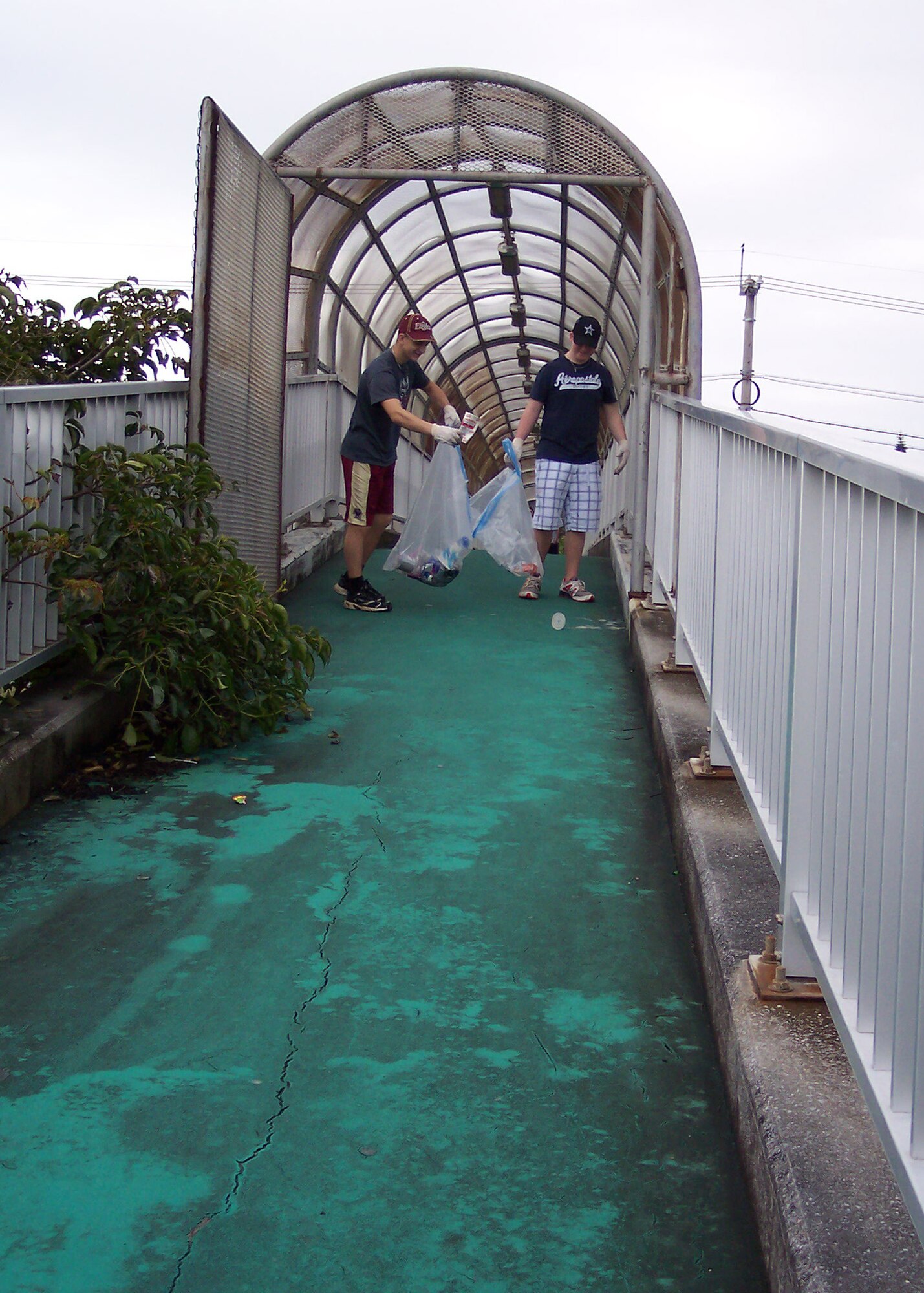 Kadena high school students, Dom Shea (left) and Jordan Sanders (right), pick up trash on an overpass bridge near Kadena Air Base and the Chibana housing area on Presidents Day, Feb. 21.  The students collected nearly three 33-gallon bags full of trash within an hour.  (Courtesy photo)