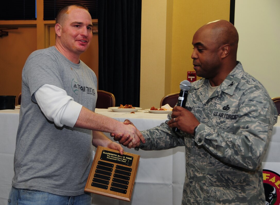 (Right to left) Col. Trent Edwards, 28th Mission Support Group commander, awards Tech. Sgt. Eddie Byrns, 28th Civil Engineer Squadron electrical systems technician, a plaque for first place during the first "Man vs. Food" competition at Ellsworth Air Force Base S.D., March 4, 2011.  Sixteen Airmen from across the base participated in the competition to see who could eat a dozen “atomic” hot wings within three minutes. (U.S. Air Force photo/Senior Airman Anthony Sanchelli)

