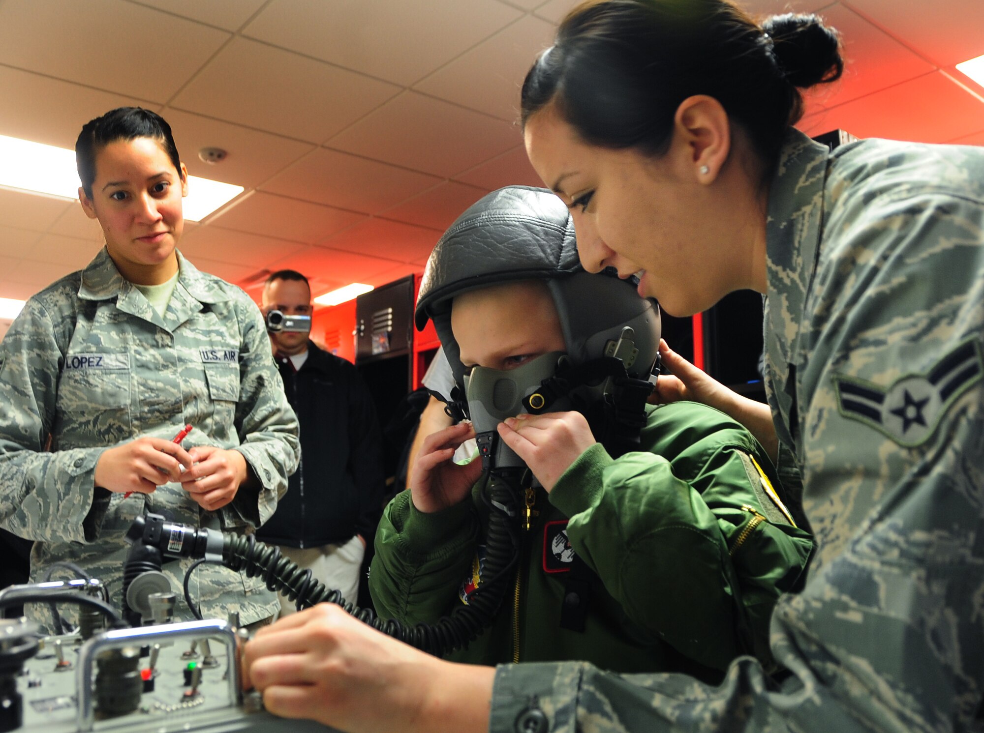 Eight-year-old Noah Misselt from Box Elder, S.D., tests his flight helmet with help from Airman 1st Class Jory Bordreaux and Senior Airman Jennifer Lopez, 34th Bomb Squadron aircrew flight equipment technicians, during the Aircrew for a Day program at Ellsworth Air Force Base, S.D., March 4, 2011.  Noah was diagnosed with leukemia in 2008, and began chemotherapy almost immediately. (U.S. Air Force photo/Senior Airman Anthony Sanchelli)  
