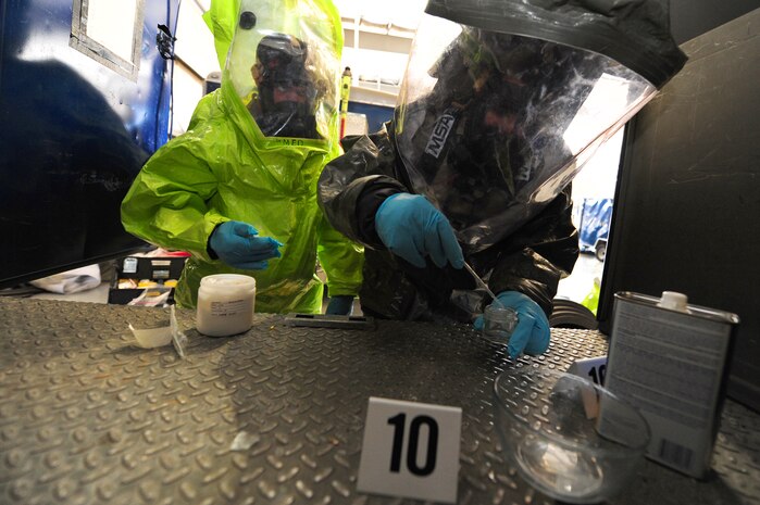 Airman 1st Class Drew Witter and Senior Airman Harry Sayan Diaz, 99th Civil Engineer Squadron emergency management craftsmen, collect chemicals during a simulated contamination during a Civil Support Team exercise Feb. 24.  A CST has the capability of responding to chemical, biological, radiological and nuclear agents during natural and manmade disasters.   (U.S. Air Force Photo by Staff Sgt. William P. Coleman)