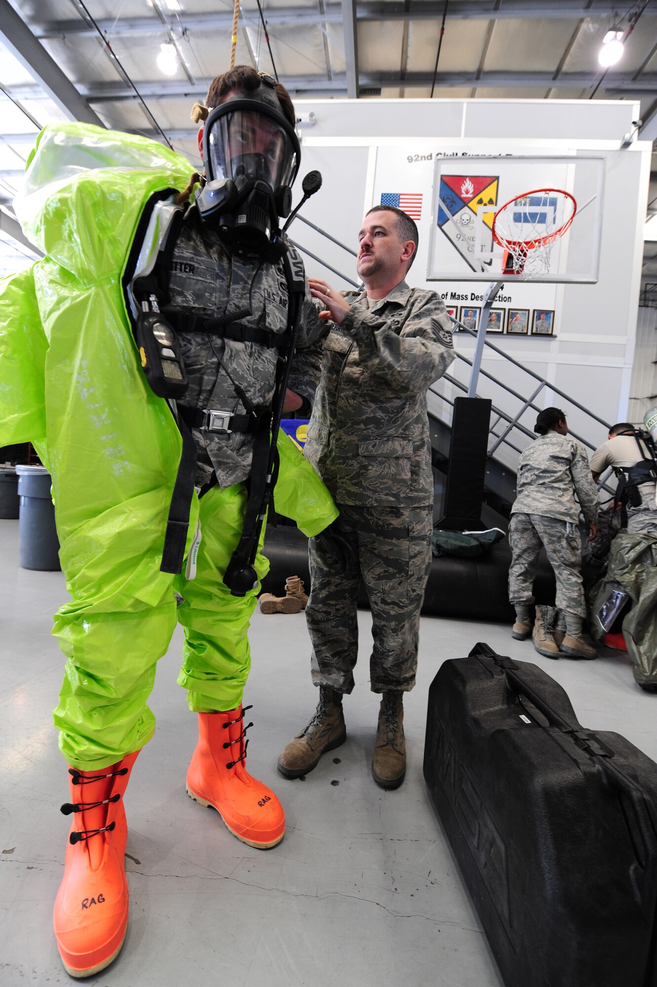 Tech. Sgt. Jeffrey Berry, 99th Civil Engineer Squadron, noncommissioned officer in charge of emergency management assists Airman 1st Class Drew Witter, 99 CES  emergency management craftsman, don a chemical suit during a Civil Support Team exercise Feb. 24.  A CST has the capability of responding to chemical, biological, radiological and nuclear agents during natural and manmade disasters.   (U.S. Air Force Photo by Staff Sgt. William P. Coleman)
