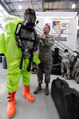 Tech. Sgt. Jeffrey Berry, 99th Civil Engineer Squadron, noncommissioned officer in charge of emergency management assists Airman 1st Class Drew Witter, 99 CES  emergency management craftsman, don a chemical suit during a Civil Support Team exercise Feb. 24.  A CST has the capability of responding to chemical, biological, radiological and nuclear agents during natural and manmade disasters.   (U.S. Air Force Photo by Staff Sgt. William P. Coleman)