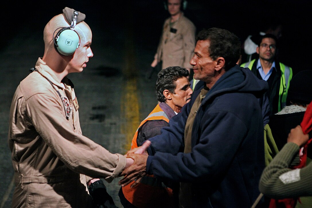 U.S. Marine Corps Cpl. Brandon Shirley shakes hands with an evacuee leaving a KC-130J Hercules aircraft after arriving in Cairo, Egypt, March 5, 2011. The Marines are  helping evacuate Egyptians, who fled to the Tunisian border from Libya, get back to Egypt. Shirley, a loadmaster, is assigned to the 26th Marine Expeditionary Unit. 