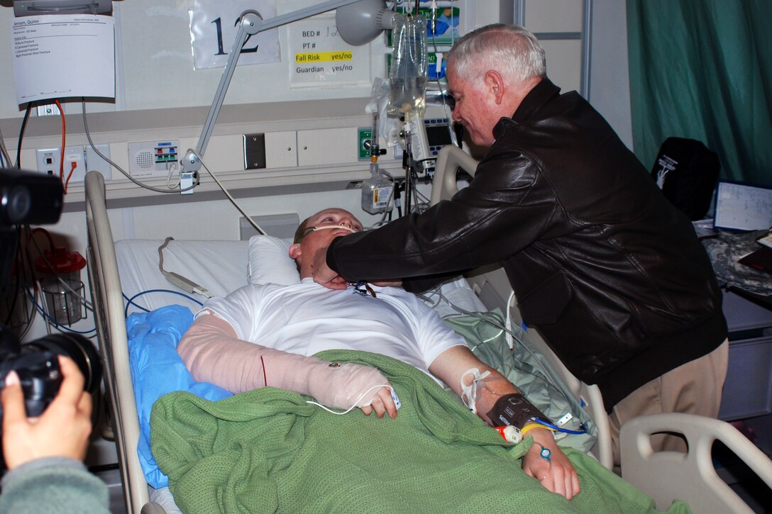 U.S. Defense Secretary Robert M. Gates pins the Purple Heart Medal and a Combat Action Badge on the chest of U.S. Army Spc. Quinn Jensen at the Heathe N. Craig Joint Theater Hospital at Bagram Air Field, March 7, 2011. Jensen is assigned to the 744th Engineer Company, 54th Engineer Battalion.