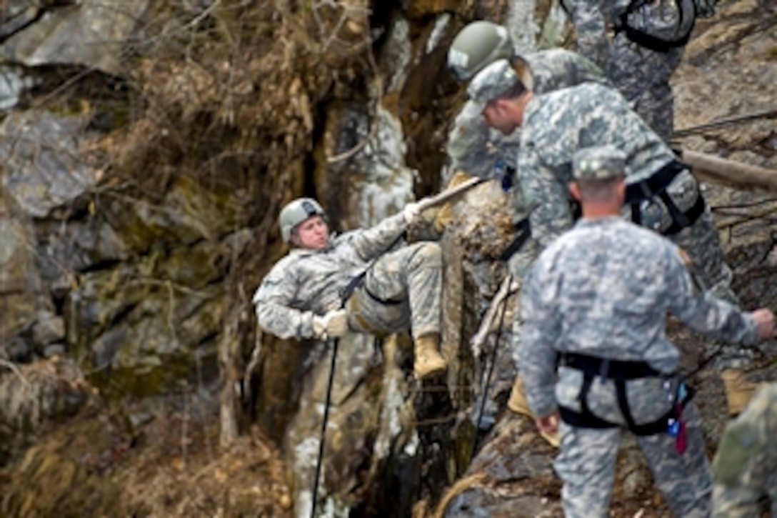 U.S. Army Ranger instructors watch as an Army Ranger student rappels down the side of a 60-foot rock face at Camp Frank D. Merrill, in Dahlonega, Ga., on Feb. 20, 2011.  The students learn mountaineering skills, including rappelling and knot tying during the course.  