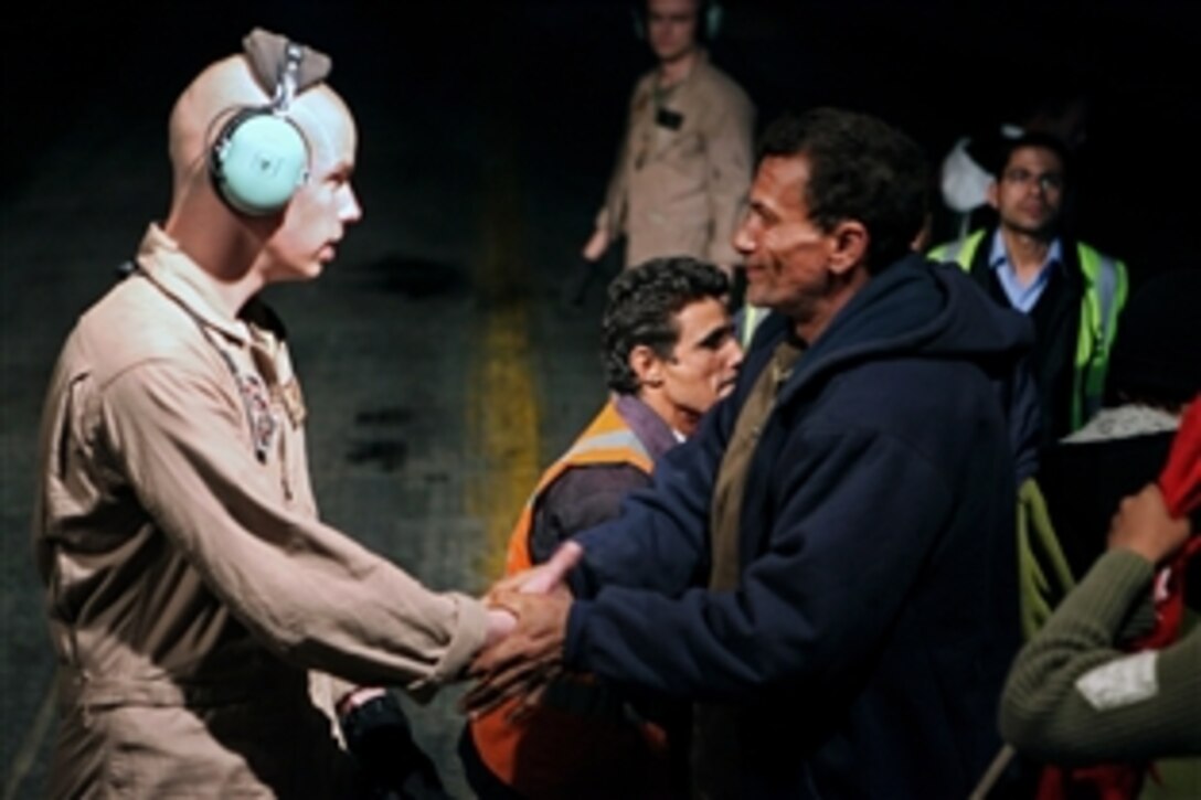 U.S. Marine Corps Cpl. Brandon Shirley, left, shakes hands with an evacuee leaving a U.S. Air Force KC-130J Hercules aircraft after arriving in Cairo, Egypt, March 5, 2011. The U.S. government is working with the international community to meet the humanitarian needs of the Libyan people and others in their country who fled across the border because of political unrest.