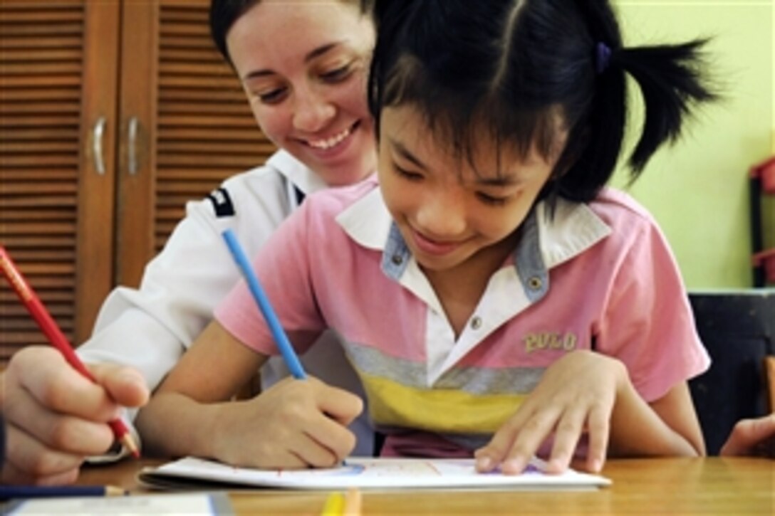 U.S. Navy Seaman Krista Stelzner draws pictures with a child during a community service event at the Bukit Harapan Therapeutic Community Center, in Sepangar, Malaysia, March 2, 2011. Stelzner is assigned to the USS Blue Ridge, which is making its first port call in Malaysia in a year. The center is a home for orphaned and disabled children.