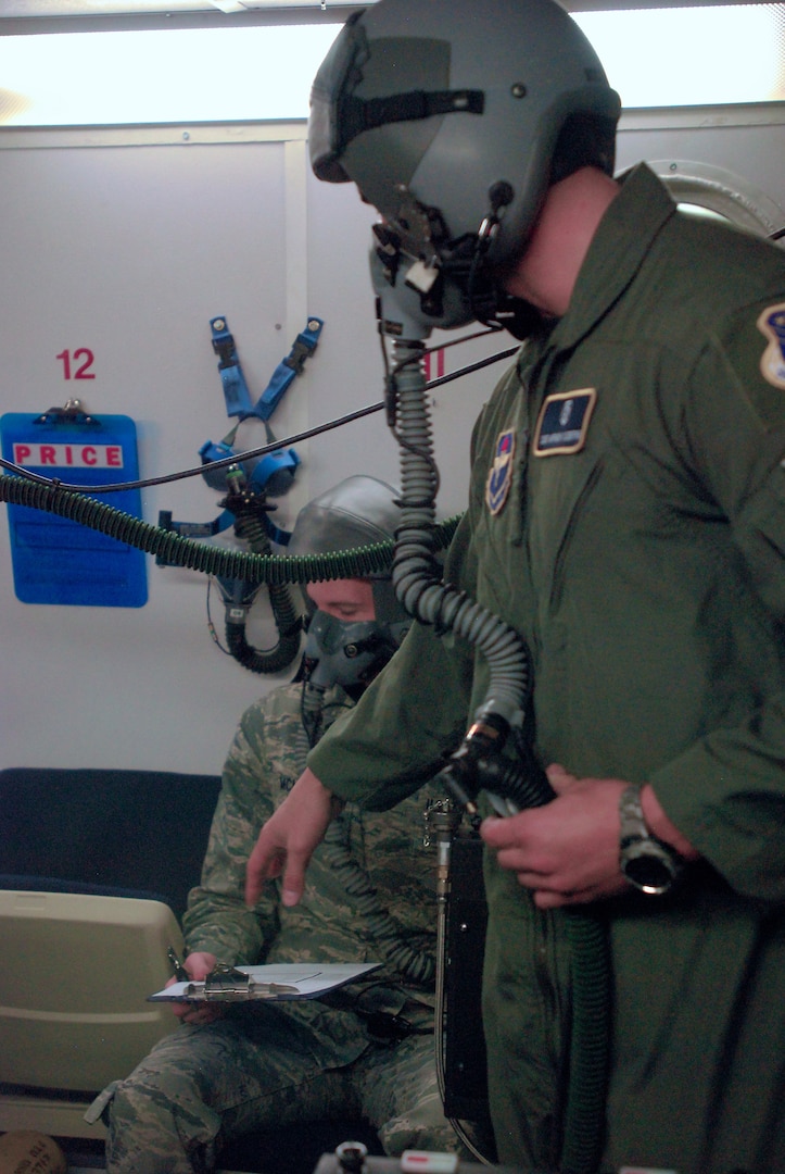 An inside observer during altitude training in a hypobaric chamber keeps an eye on a fellow Airman ? both are aerospace physiologists with the 359th Aeromedical Squadron -- while he reads a worksheet designed to keep trainees? minds occupied, which makes the training more closely resemble actual flight in an aircraft. (U. S. Air Force photo/Brian McGloin)
