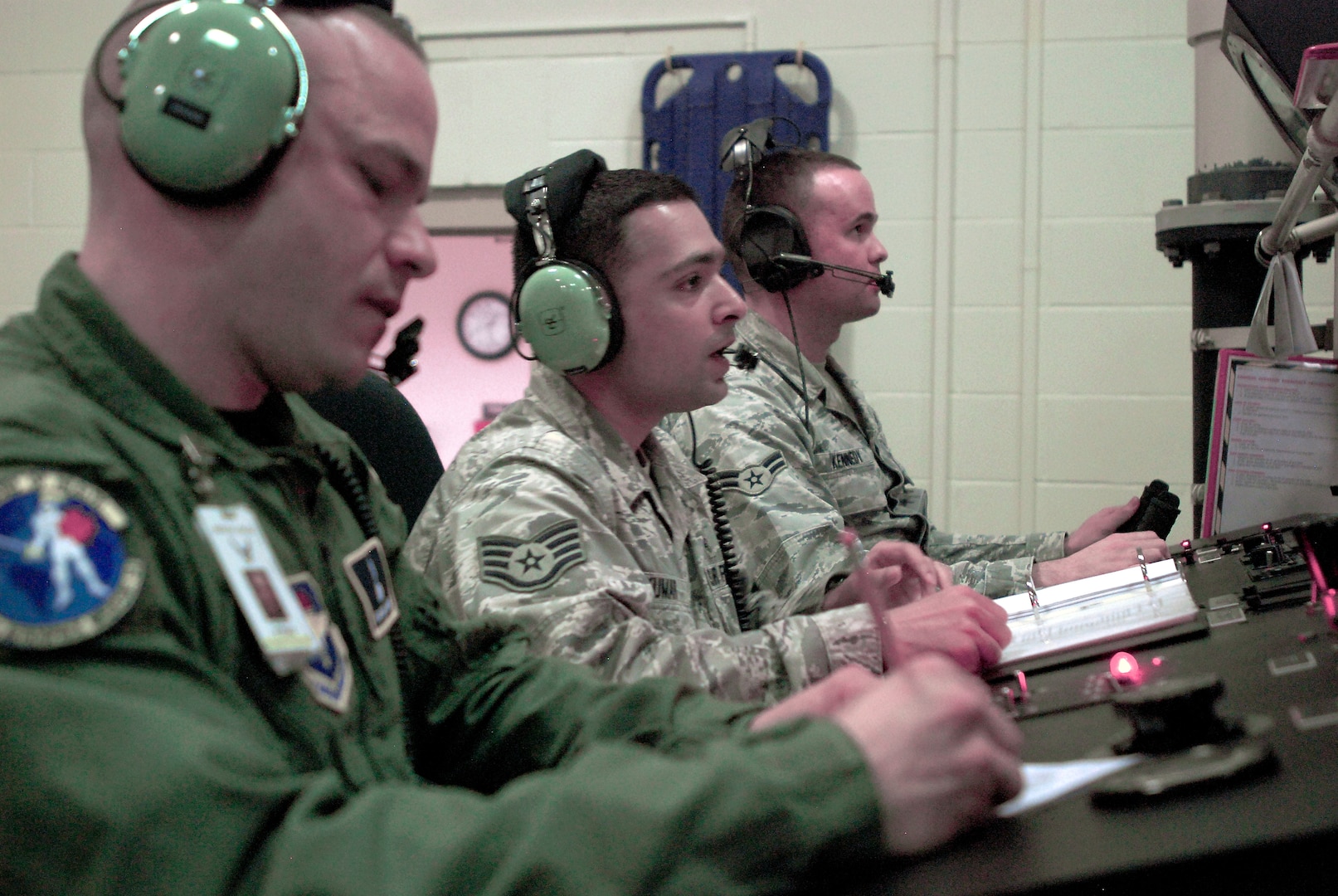 Aerospace physiologists from the 359th Aeromedical Squadron, Randolph Air Force Base, Texas, at the controls of a hyperbaric chamber during altitude training. Tech. Sgt. Michael Stegen takes notes while working as a recorder, similar to a court stenographer. Next to him, Staff Sgt. Vikas Kumar speaks with an inside observer while looking at her through the window (just out of the frame). In the background, Airman 1st Class Joseph Kennedy controls the barometric pressure in the chamber, simulating the effects of flight and altitude. (U. S. Air Force photo/Brian McGloin)
