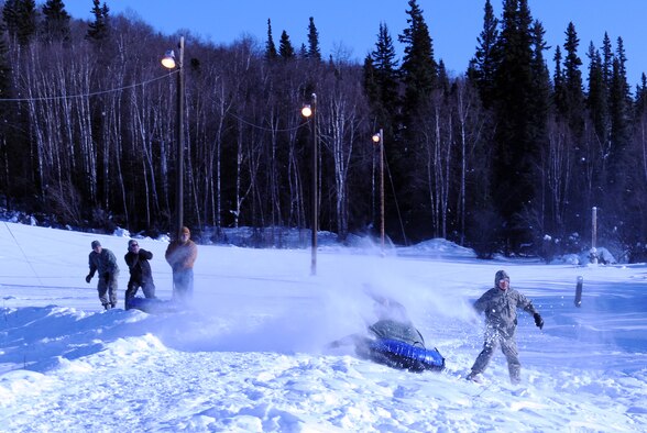 An Airman sprays snow as he races an inner tube down Iceman Falls March 4, 2011, Eielson Air Force Base, Alaska. Dozens of Airmen participated in several winter carnival events, which was held as a customer appreciation event. (U.S. Air Force photo/ Airman 1st Class Janine Thibault)