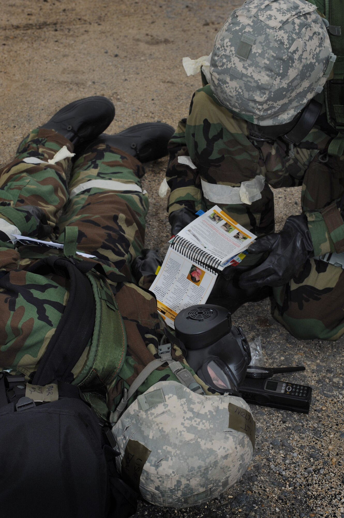 An Airman references his Airman's Manual to assist his partner as he became a simulated casualty at Base Y on Joint Base Pearl Harbor-Hickam, Hawaii during the Operational Exercise March 5. The ORE tested Airmen's ability to respond to survive and operate during various wartime conditions. (U.S. Air Force photo/Airman1st Class Lauren Main)