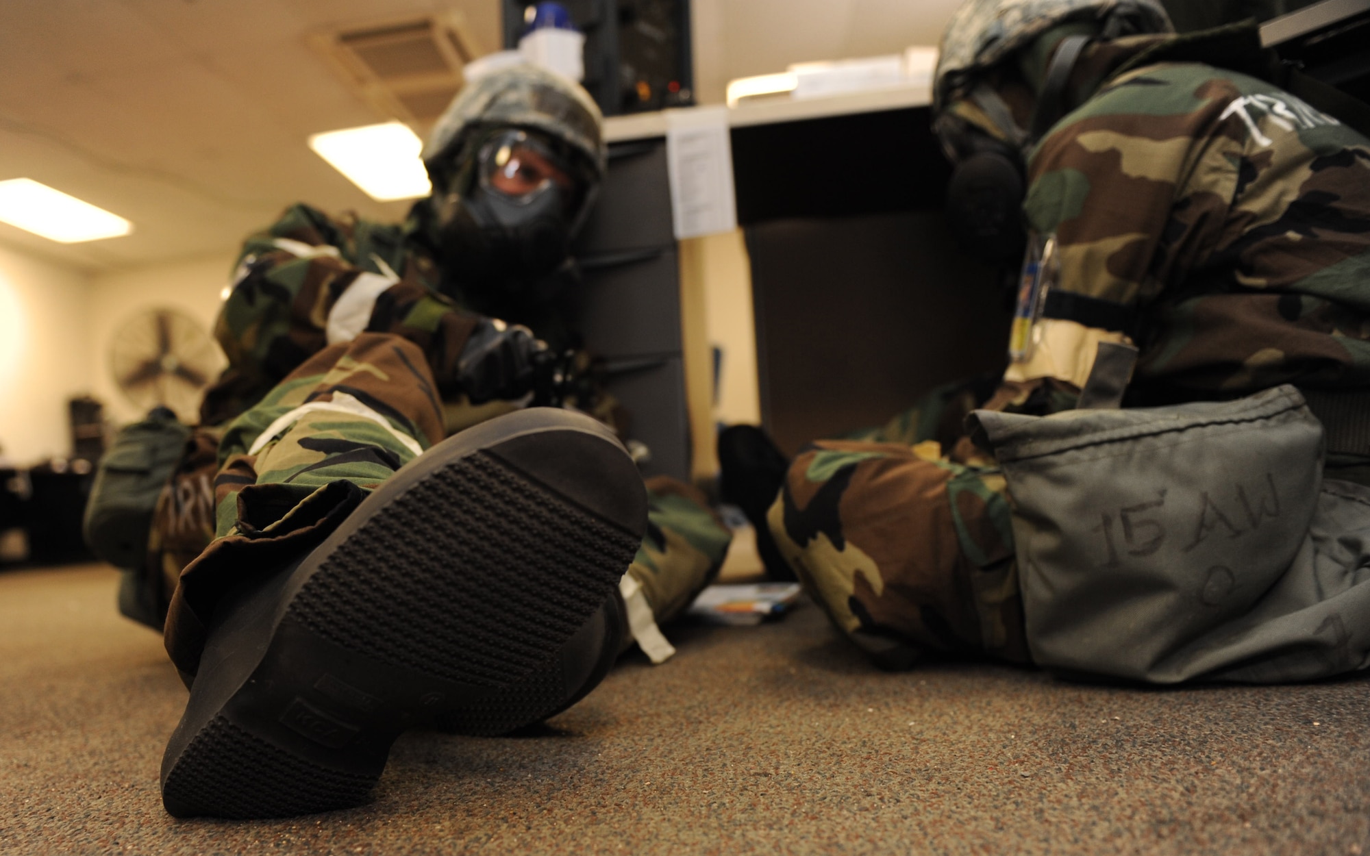 Airmen hunker down and take shelter during alarm red in mission oriented protective posture gear at Base Y on Joint Base Pearl Harbor-Hickam, Hawaii during the Operational Exercise March 5. The ORE tested Airmen's ability to respond to survive and operate during various wartime conditions. (U.S. Air Force photo/Airman1st Class Lauren Main)
