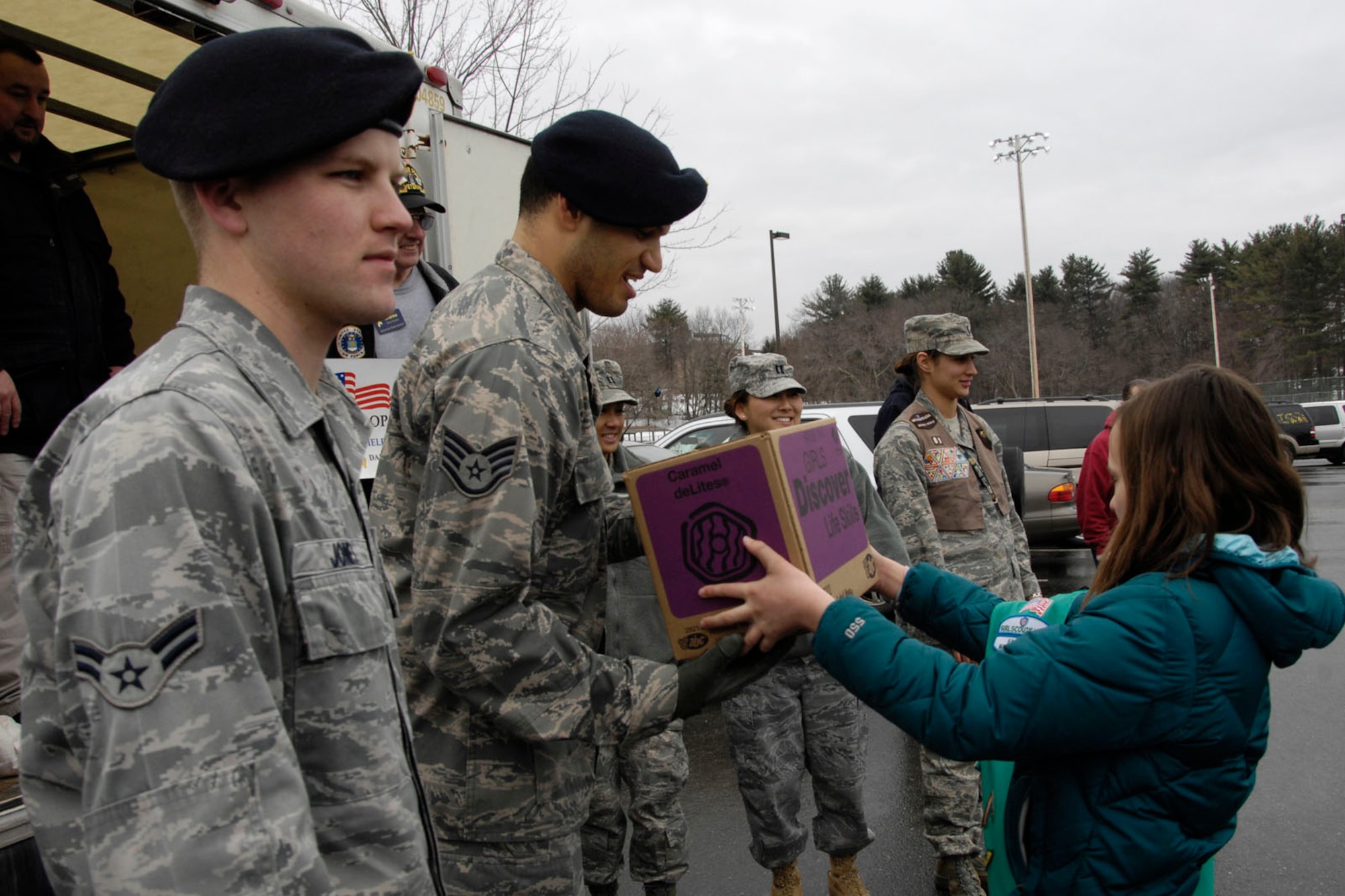 HANSCOM AIR FORCE BASE, Mass. – A Girl Scout hands a box of cookies to Staff Sgt. Scott Roy during Operation Cookie Drop on March 5. More than 1,500 Girl Scouts dropped off approximately 30,000 boxes of cookies to 11 troop-focused non-profit organizations and military and federal government agencies during the one-day event. (U.S. Air Force photo by Linda LaBonte Britt)