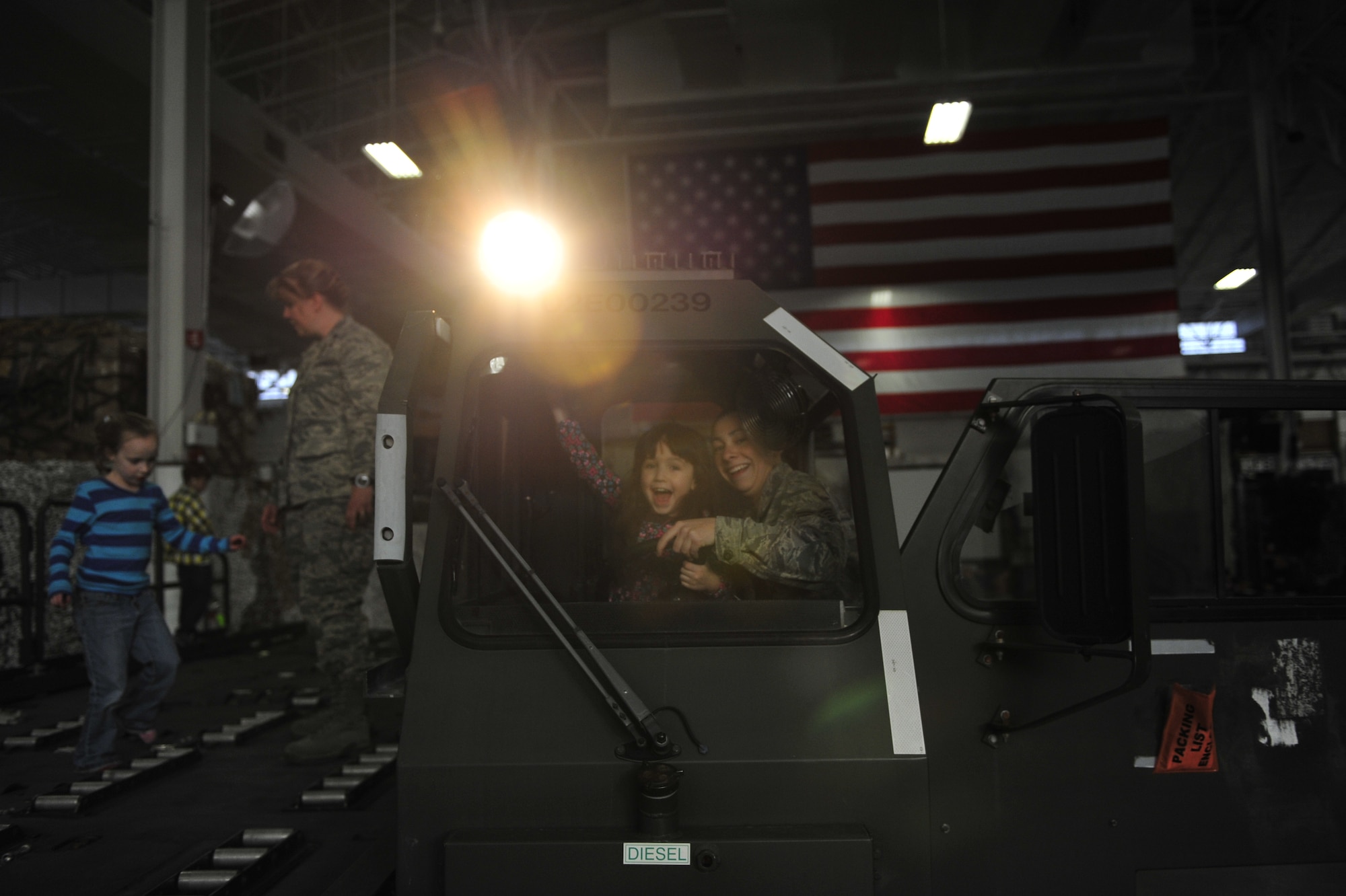 Kelly Burrows, six-year-old daughter of Master Sgt. Stephen Burrows, 621st Contingency Operations Support Group first sergeant, aims the spotlight of a next-generation small loader with the help of Staff Sgt. Jessica Flores, 819th Global Support Squadron in-transit visibility manager, during the 621st Contingency Response Wing’s family open house at the Joint Base McGuire-Dix-Lakehurst, N.J. Global Reach Deployment Center March 4.  The event included activities and food for the families alongside demonstrations of the specialized equipment used by the unit to provide emergency global mobility support to humanitarian crises and national defense operations. (U.S. Air Force photo/Tech. Sgt. Parker Gyokeres) (Released)
