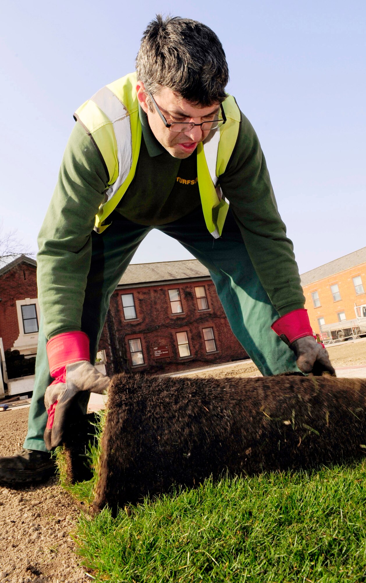 RAF MILDENHALL, England -- Glyn Tunney, a local contractor, lays turf during the landscaping at Washington Square here March 8, 2011. The Washington Square project will contribute to the Air Force initiatives for going green by removing hard surfaces that contribute to storm water pollution and reducing vehicular pollution caused by driving through the campus. (U.S. Air Force photo/Senior Airman Ethan Morgan) 
