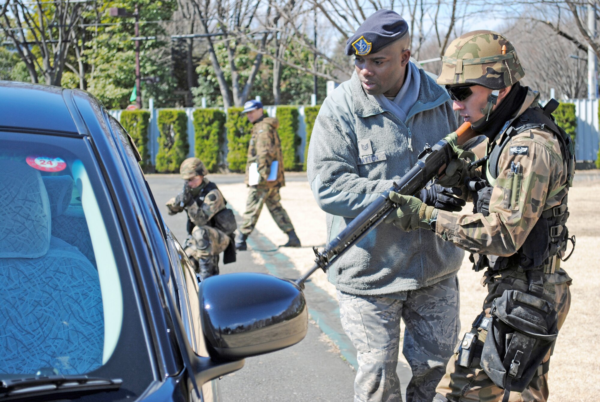 Tech. Sgt. Johnnie Payton trains a security guard from the Japan Air Self Defense Force on how to properly approach a suspicious vehicle during field training March 4, 2011, at Yokota Air Base, Japan. Airmen from 5th Air Force and 374th Airlift Wing are helping to train approximately 35 JASDF security guards as they prepare to stand up the Air Self Defense Force's first squadron devoted to advanced security training. Sergeant Payton is the 374th Security Forces Squadron flight chief. (U.S. Air Force photo/Capt. Will Powell)