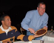 DEL RIO, Texas –Lieutenant Col. Oliver "Tic" Bonney, 87th Fighter Training Squadron assistant director of operations, is anxious to share a piece of his Kentucky Derby Pie while Maj. Karamo Hayward,  47th Fighter Training Wing inspector general’s staff eagerly assists. Bonney won the bid for the pie during the second annual Laughlin Officers’ Spouses Club charitable auction. (U.S. Air Force Photo by Master Sgt. Peter Borys)