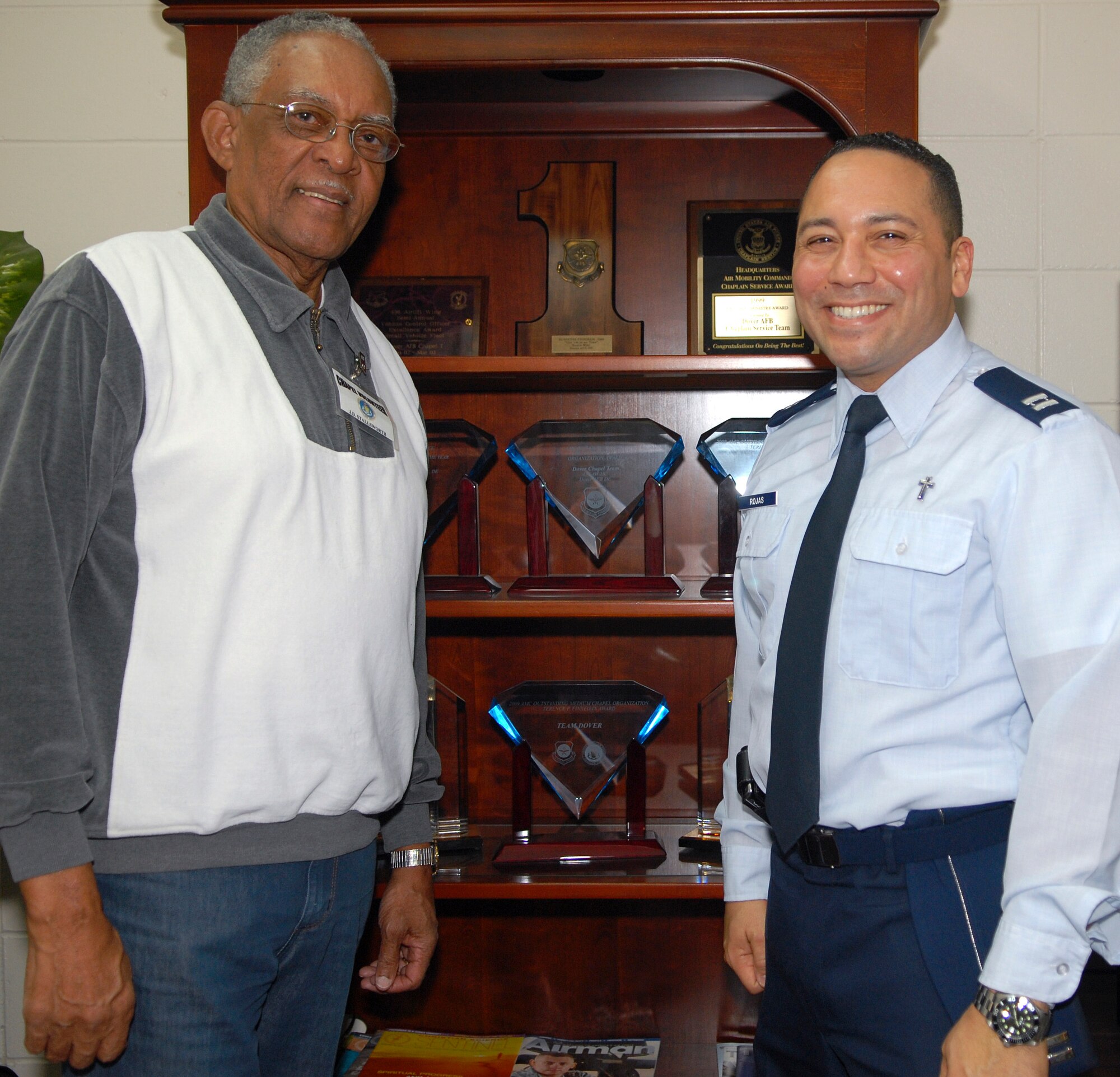 J.D. Stallsworth, left, base chapel volunteer coordinator, and Chaplain (Capt.) Richard Rojas showcase the numerous awards the base chapel has earned throughout the years. The chapel is nominated for the Air Force's Best Medium-Size Chapel Award this year. (U.S. Air Force photo by Airman 1st Class Samuel Taylor)