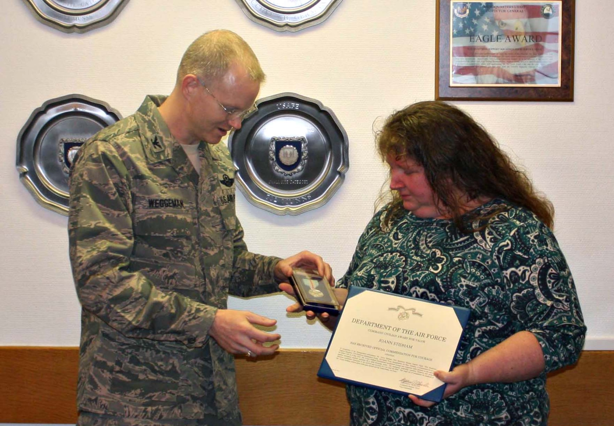 BUECHEL AIR BASE, Germany – Col. Christopher Weggeman, 52nd Fighter Wing commander, presents Joann Stidham, wife of Tech. Sgt. Christian Stidham, 702nd Munitions Maintenance Squadron in Buechel Air Base, Germany, the Command Civilian Award for Valor Feb. 24. Ms. Stidham was presented the award for her role in saving a then 2-year-old boy’s life in Faid, Germany, in May 2009. (U.S. Air Force photo/Senior Master Sgt. Tammy Robel) 
