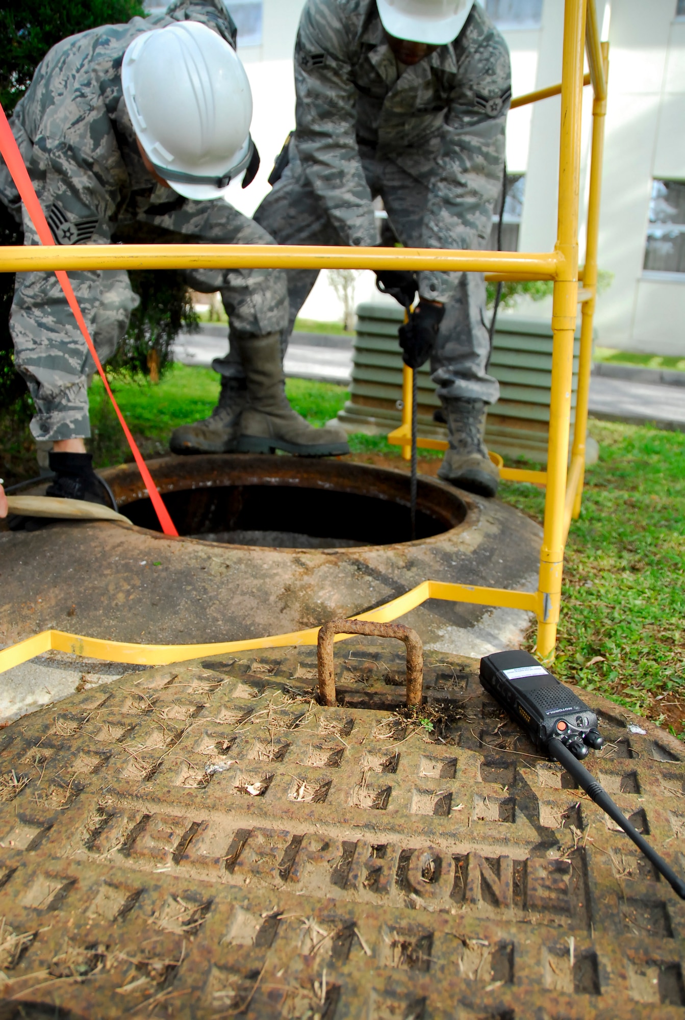 Staff Sgt. David Hollars, cable and antenna systems supervisor (left), and Airman 1st Class Romeo Rivers, cable and antenna systems technician, both from the 18th Communication Squadron, lower equipment into a telephone manhole by Kadena’s Shogun Inn, March 8. The cable and antenna systems section is responsible for rerouting essential communication cables through each office and maintaining pre-existing lines on Kadena, to keep the 18th Wing working efficiently throughout its numerous missions and responsibilities. ((U.S. Air Force photo/Airman 1st Class Maeson L. Elleman)