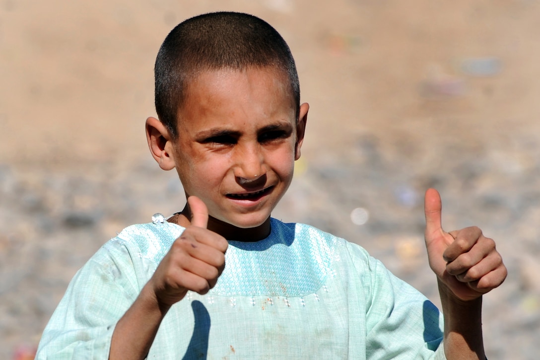 An Afghan boy gestures with his thumbs up as U.S. Defense Secretary Robert M. Gates tours the village of Tabin in Afghanistan, March 8, 2011.