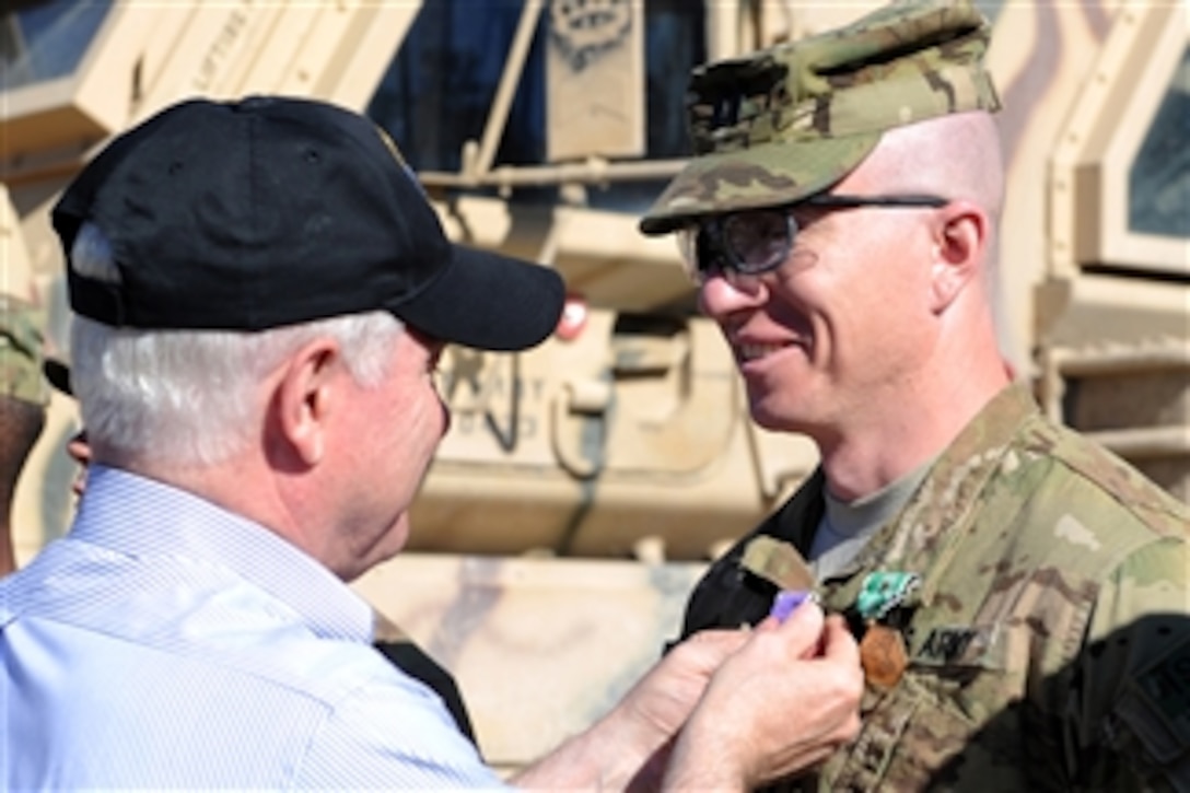 Secretary of Defense Robert M. Gates presents the Purple Heart and the Army Commendation Medal with Valor to Army Capt. Jeffrey Mackinnon, 1st Battalion, 320th Field Artillery Regiment, 2nd Brigade Combat Team, 101st Airborne Division (Air Assault) at Combat Outpost Kowall in Afghanistan on March 8, 2011.  