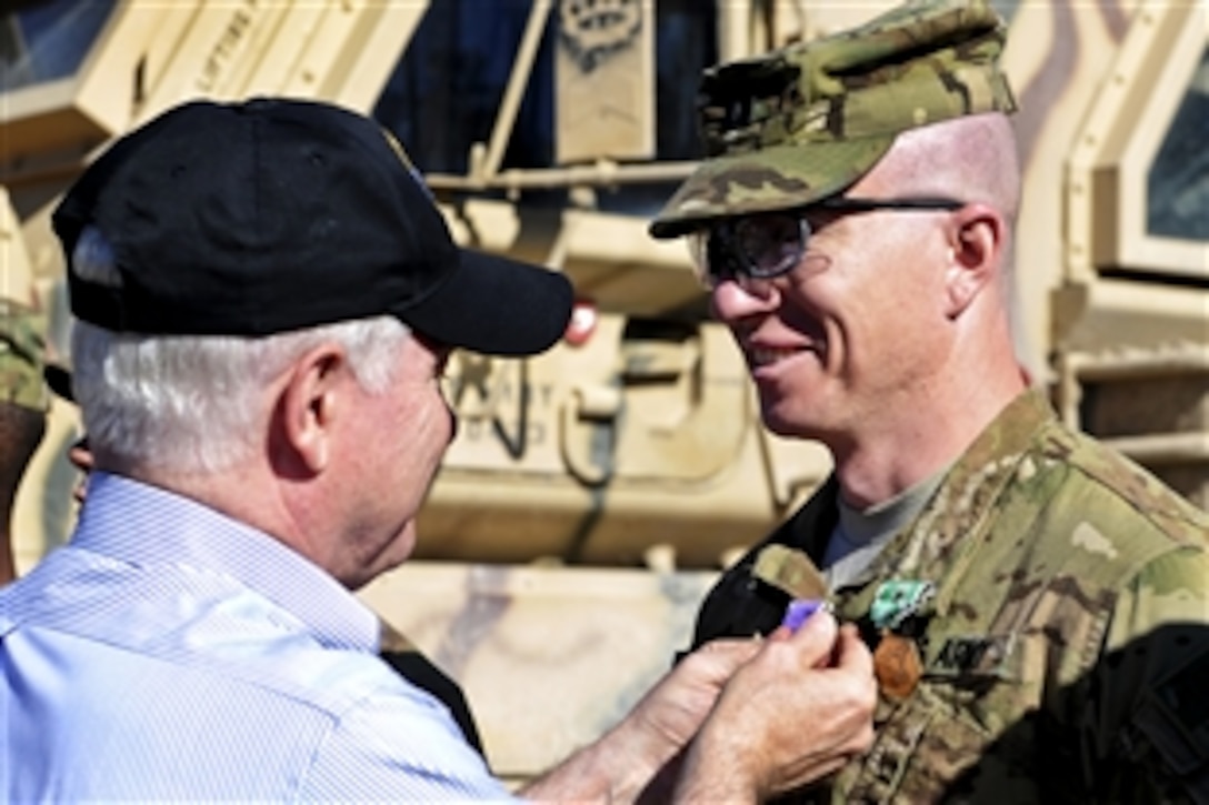 U.S. Defense Secretary Robert M. Gates presents the Purple Heart and the Army Commendation Medal with Valor to U.S. Army Capt. Jeffrey Mackinnon on Combat Outpost Kowall in Afghanistan, March 8, 2011. MacKinnon is assigned to the 101st Airborne Division's 1st Battalion, 320th Field Artillery Regiment, 2nd Brigade Combat Team.