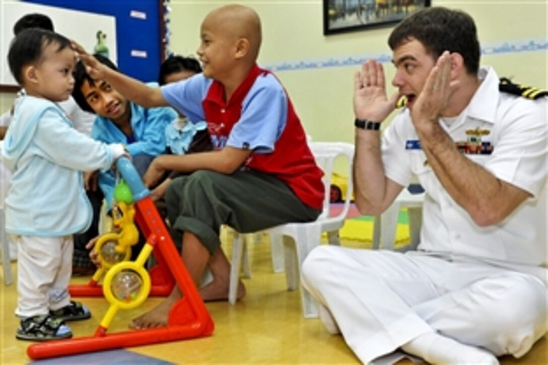 U.S. Navy Lt. Chad Tidd plays with plays with young patients in the children's ward at Hospital Likas in Sepangar, Malaysia, March 1, 2011. Tidd is from the 7th Fleet command ship USS Blue Ridge and is participating in a community service project. 