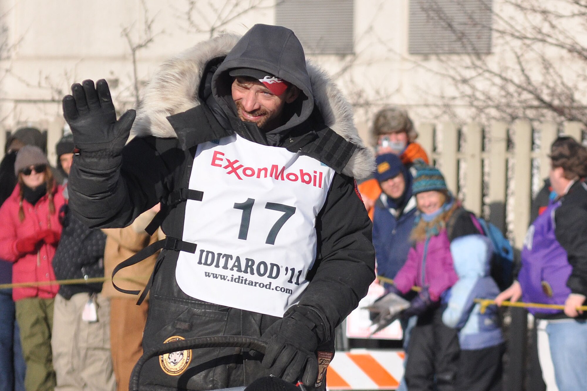 Four-time champion Lance Mackey waves to the crowd as he mushes his team down Anchorage's 5th Avenue at the ceremonial start of the 2011 Iditarod Trail Sled Dog Race March 5. Sixty-two teams, plus this year's honorary musher Tom Busch left the start point on 4th Avenue to kick off the 1,150-mile race to Nome. (U.S. Air Force photo/John Pennell)