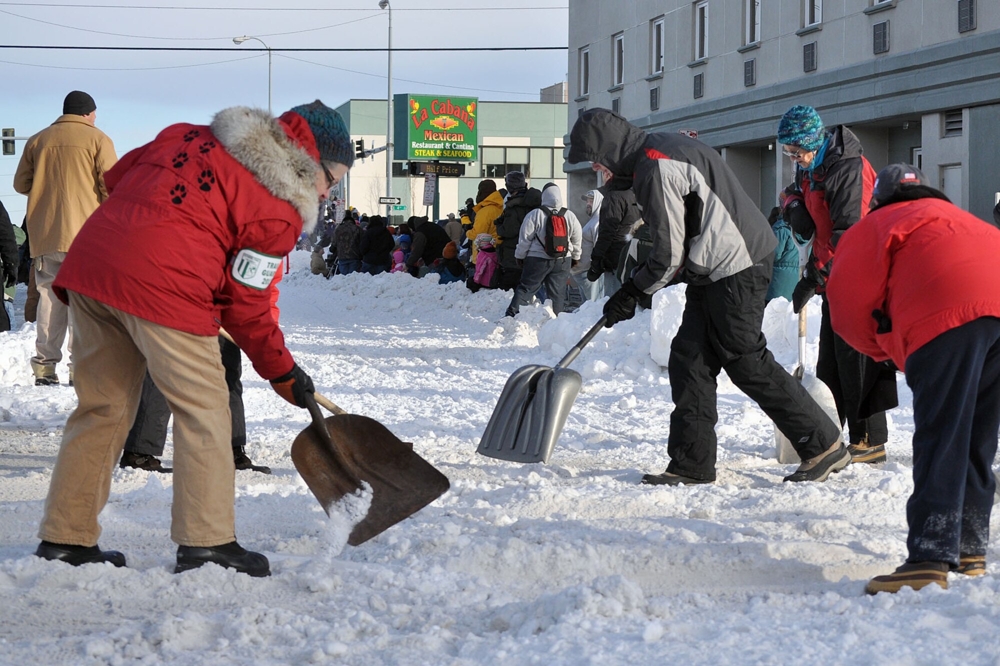 Volunteers smooth snow on the trail as it crosses Cordova Street and 5th Avenue in downtown Anchorage March 5 for the ceremonial start of the 2011 Iditarod Trail Sled Dog Race. (U.S. Air Force photo/John Pennell)
