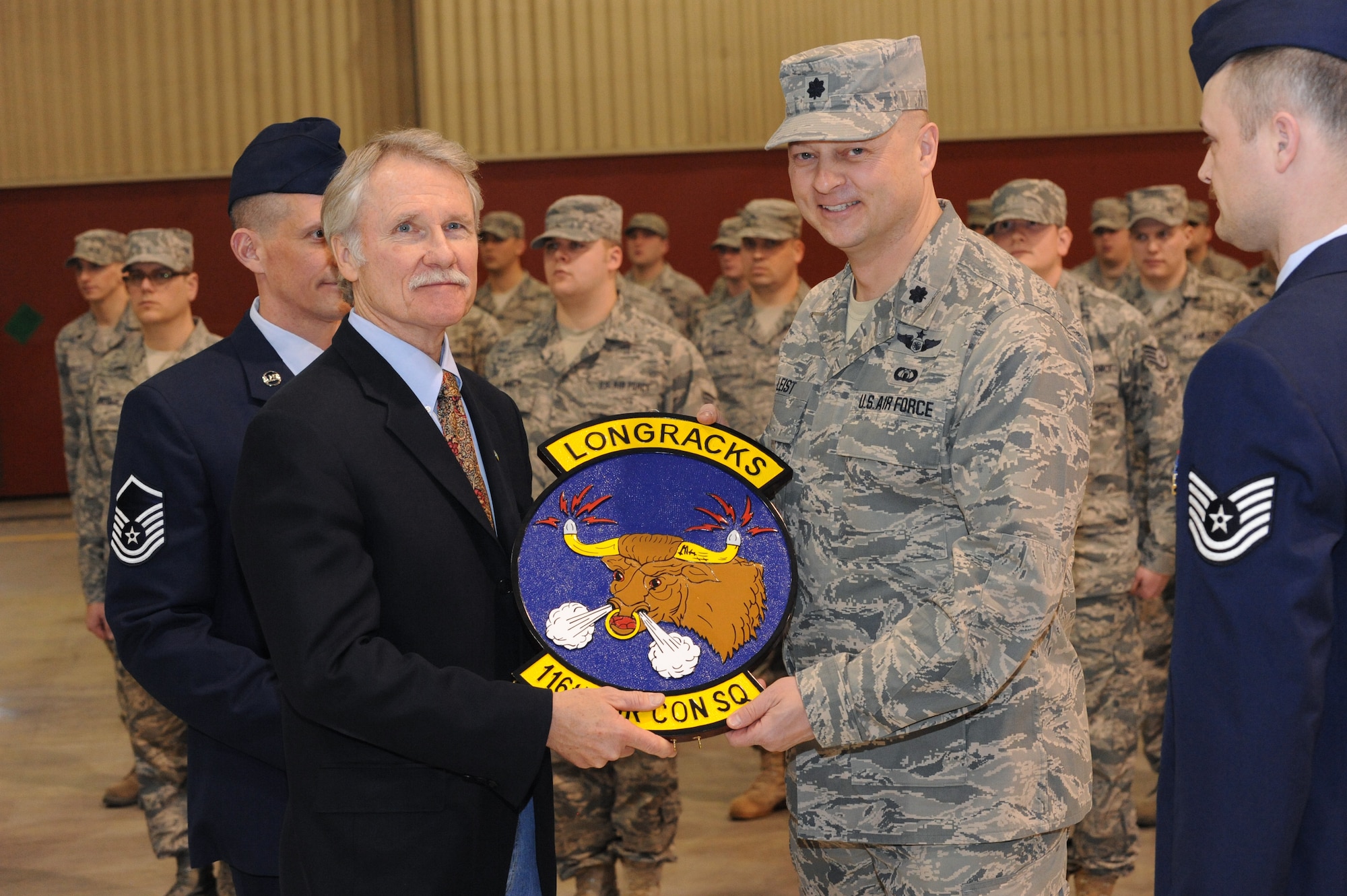 Oregon Air National Guard 116th Air Control Squadron Commander, Lt. Col. Gregor Leist (right), presents Oregon Governor John Kitzhaber with his unit's official crest, during their mobilization ceremony at the Portland Air Guard Base in Portland, Ore., Mar. 4.  More than 80 Airmen from the unit will deploy to the Middle East in support of Air Forces Central (CENTAF), where they will perform Air Battle Management missions for four months.  Kitzhaber, Maj. Gen. Raymond F. Rees, Adjutant General, Oregon; Brig. Gen. Steven Gregg, Oregon Air National Guard Commander; Congressman David Wu (OR-District 1), and other dignitaries, along with hundreds of family, friends, fellow Airmen and Soldiers attended the event.  (U.S. Air Force photograph by Tech. Sgt. John Hughel, 142nd Fighter Wing Public Affairs)