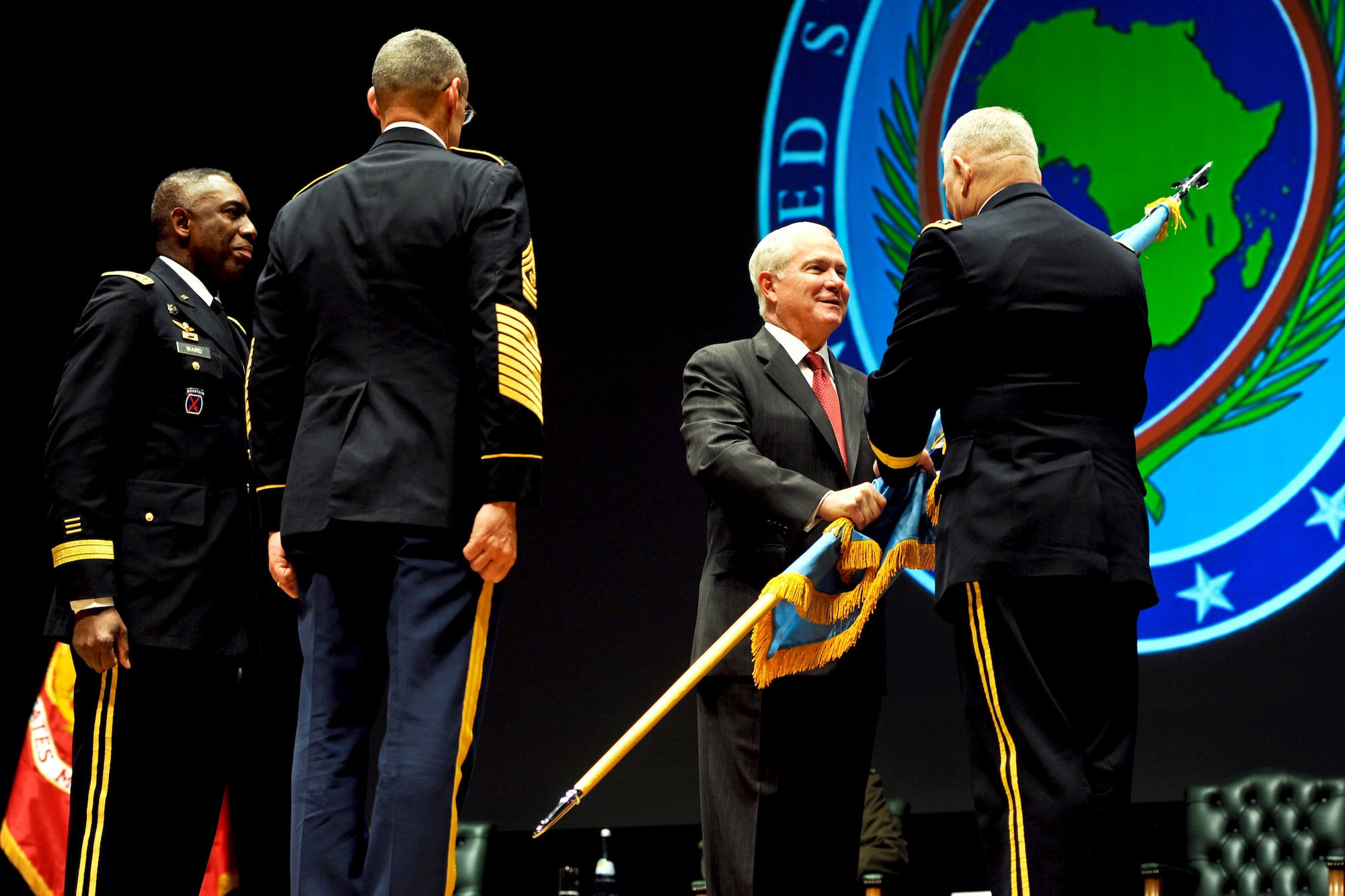 Defense Secretary Robert M. Gates passes the colors to Army Gen. Carter F. Ham, incoming commander of U.S. AFRICOM, while Army Gen. William E. “Kip” Ward (left), outgoing commander, looks on during the AFRICOM change of command ceremony at Sindelfingen Stadthalle City Hall in Stuttgart, Germany, March 9, 2011.  (Defense Department photo/Cherie Cullen)
