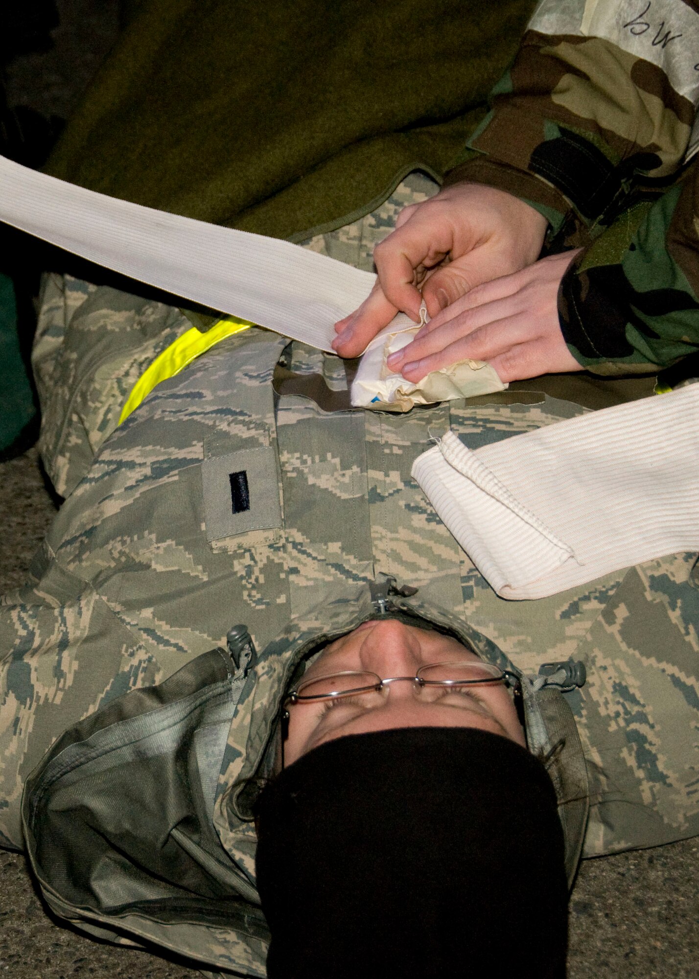 YOKOTA AIR BASE, Japan -- 1st Lt. Melissa Hughes, 459th Airlift Squadron C-12 pilot scheduler, receives treatment for a simulated open chest wound following a mock mortar attack during an Operational Readiness Exercise here March 9. Yokota members practiced self-aid buddy care during the exercise to prepare them for possible real-world contingencies. (U.S. Air Force photo/Airman 1st Class Andrea Salazar)